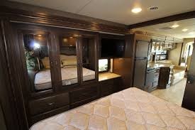 RV rental interior: bedroom view with quilted mattress, mirrored closet, TV, and full kitchen beyond.. Other Hurricane 2017