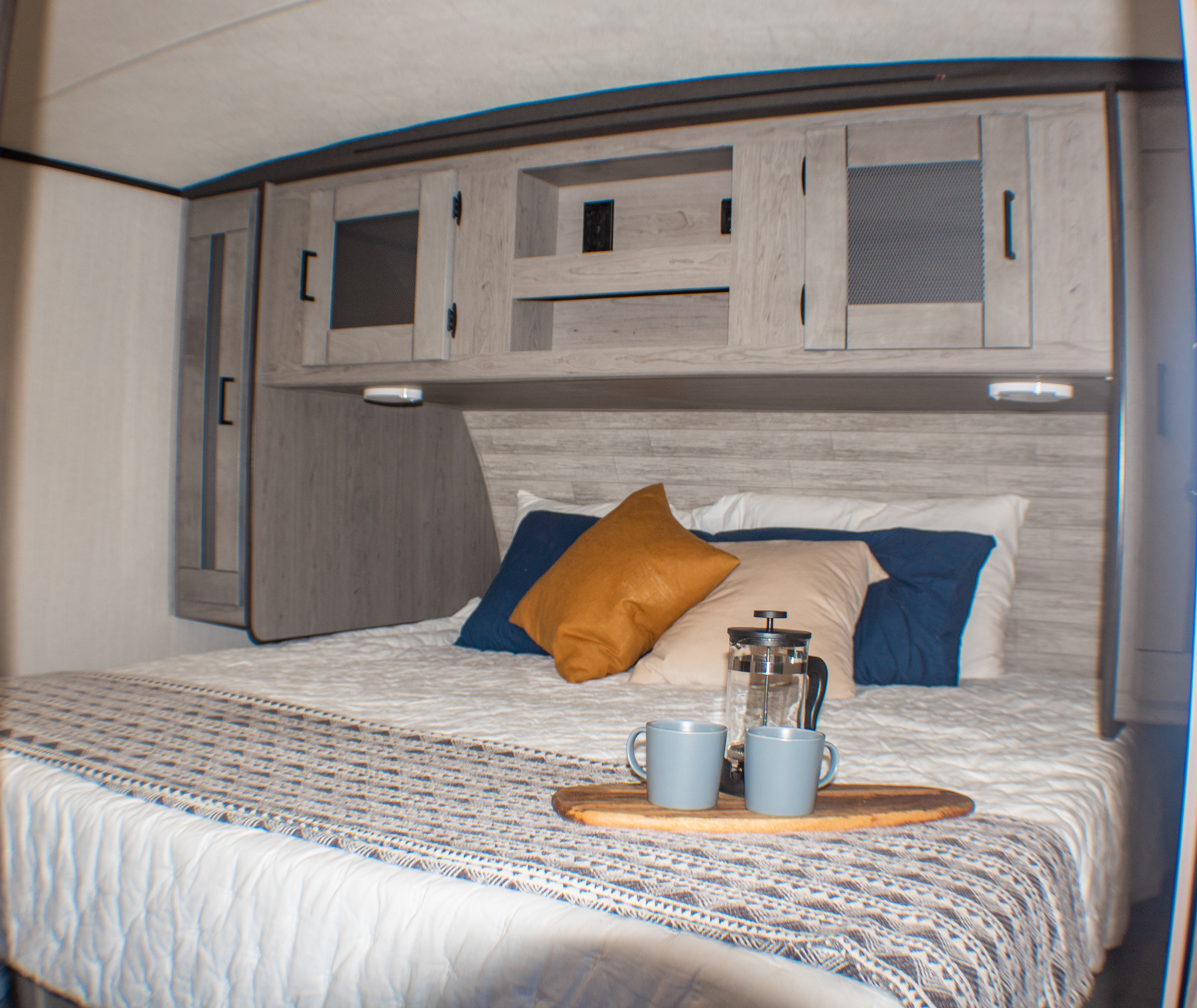 Relaxing RV rental bedroom: light-toned cabinets, a soft bed with pillows, and a coffee tray for morning comfort.. Heartland M-33 2021