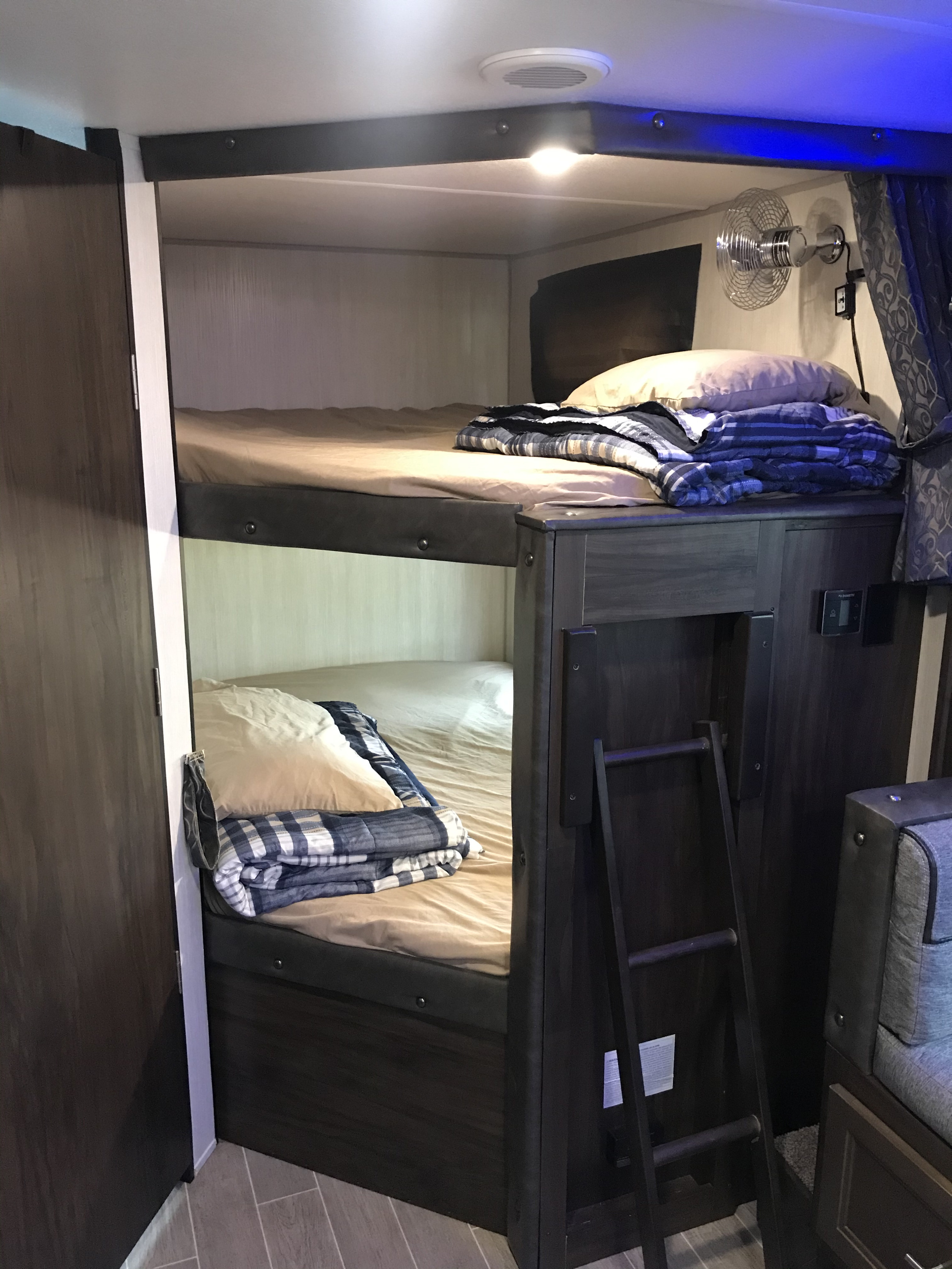 Cozy bunk beds in this RV rental, complete with a ladder and fan for comfort. Ideal for family road trips.. Forest River Grey Wolf 26DBH 2020