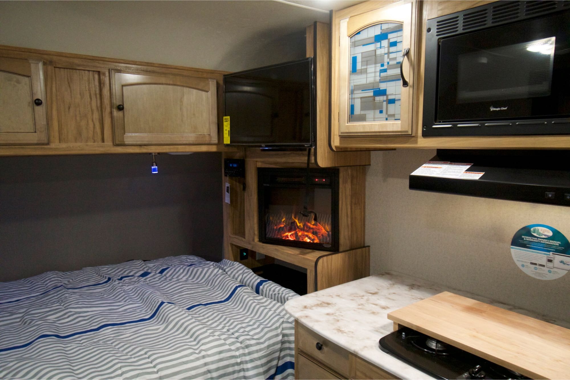 Cozy RV rental interior: bed, entertainment (TV, fireplace), & kitchenette with microwave for road trip comfort.. Coachmen Freedom Express 2019