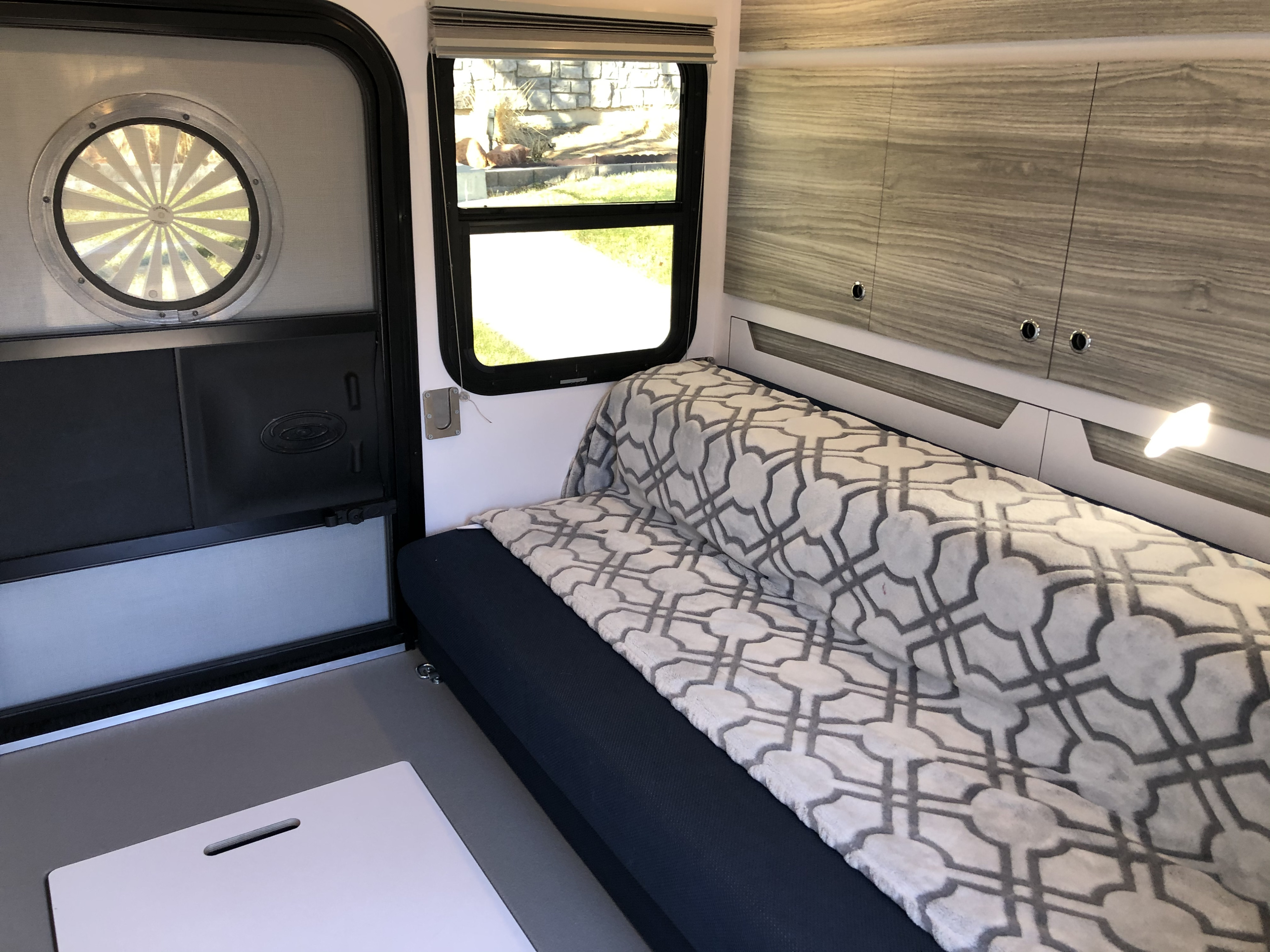 This RV rental's cozy interior features a blue sofa with a patterned blanket, wood-grain cabinets, and windows.. Bean Trailer Mean 2020