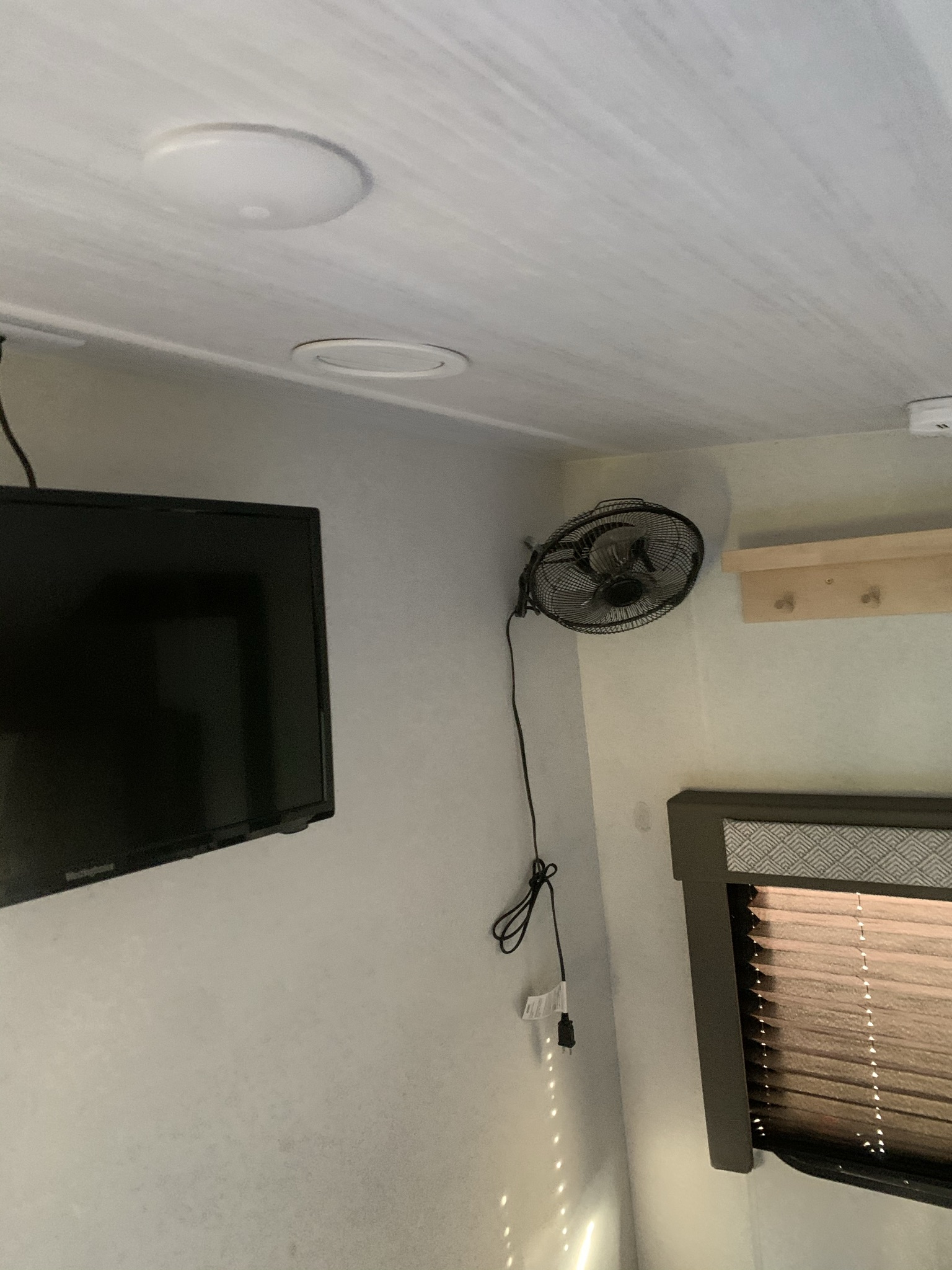 RV rental bedroom with wall-mounted TV, oscillating fan, and window blinds. Ceiling lights overhead.. Forest River Salem Cruise Lite 2020