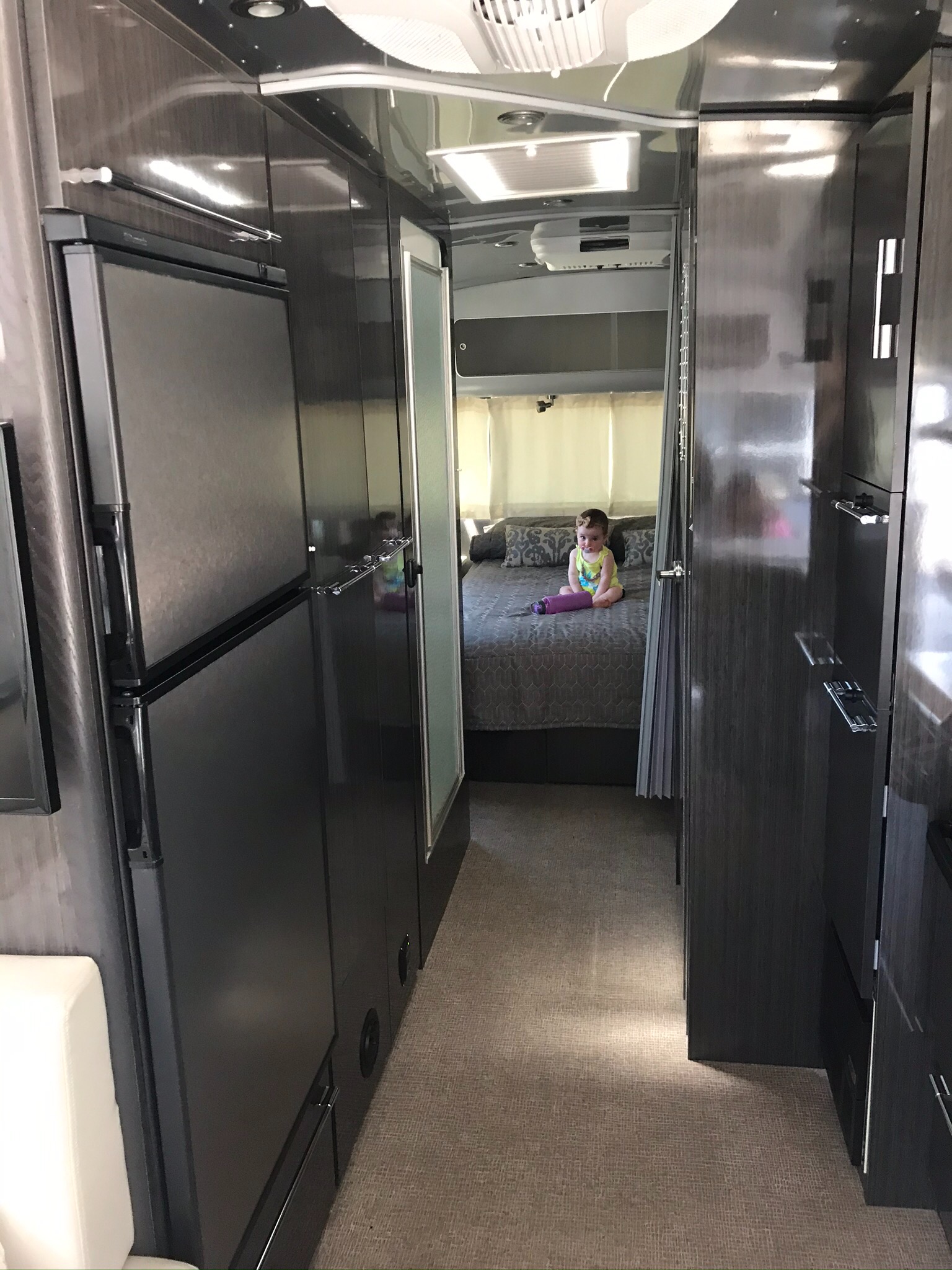 RV rental interior: child in bedroom past galley kitchen and storage units, highlighting compact living.. Airstream International 2014