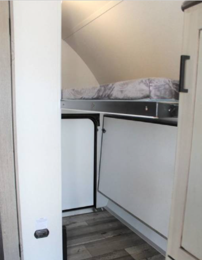 RV rental interior featuring a cozy bunk bed, adaptable storage space, and attractive wood-look flooring.. Keystone Outback 2021