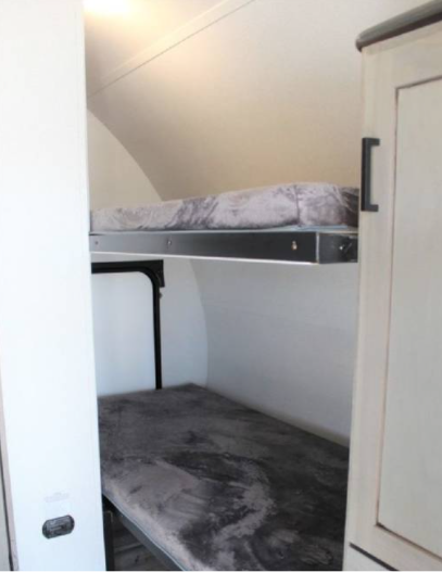 RV rental's bunk beds: two sleeping berths with grey mattresses, one above the other, in a compact camper interior.. Keystone Outback 2021
