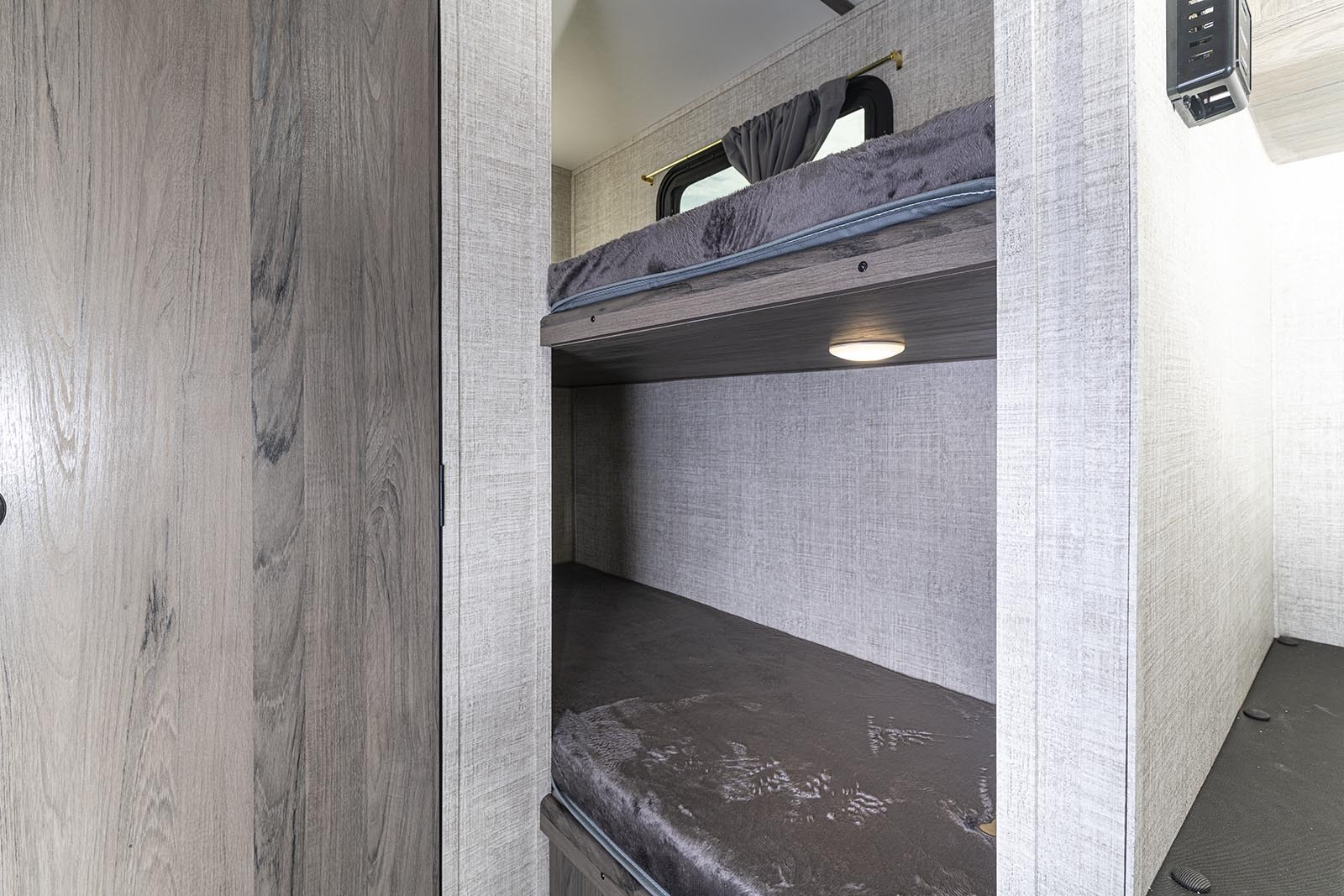 Inside an RV rental, comfortable bunk beds offer sleeping space with a window, reading light, and charging ports.. Gulf Stream Amerilite 2021