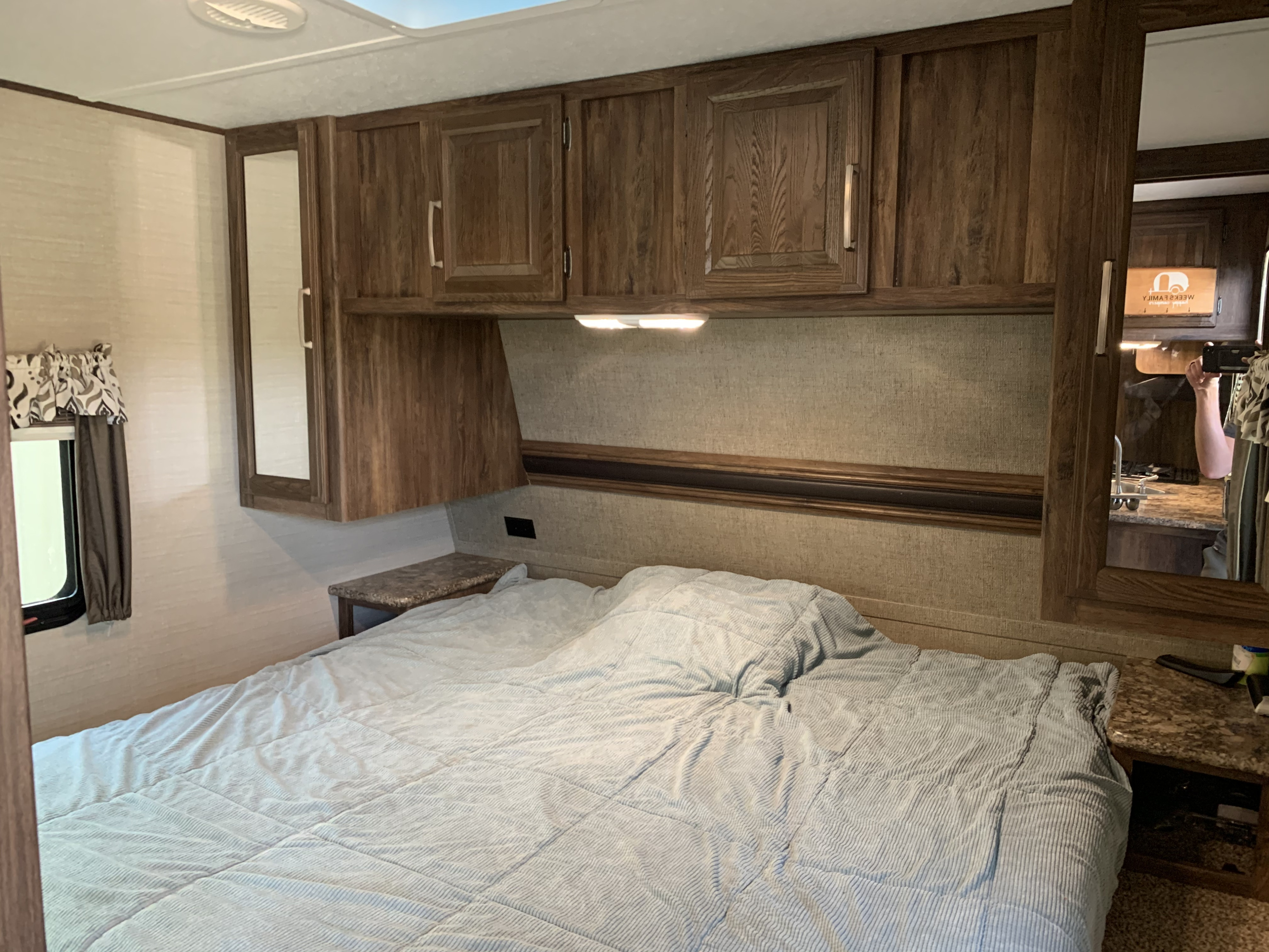 Cozy RV rental bedroom features a comfy bed, wooden overhead cabinets, and built-in mirrors.. Keystone Cougar Half-Ton 2017