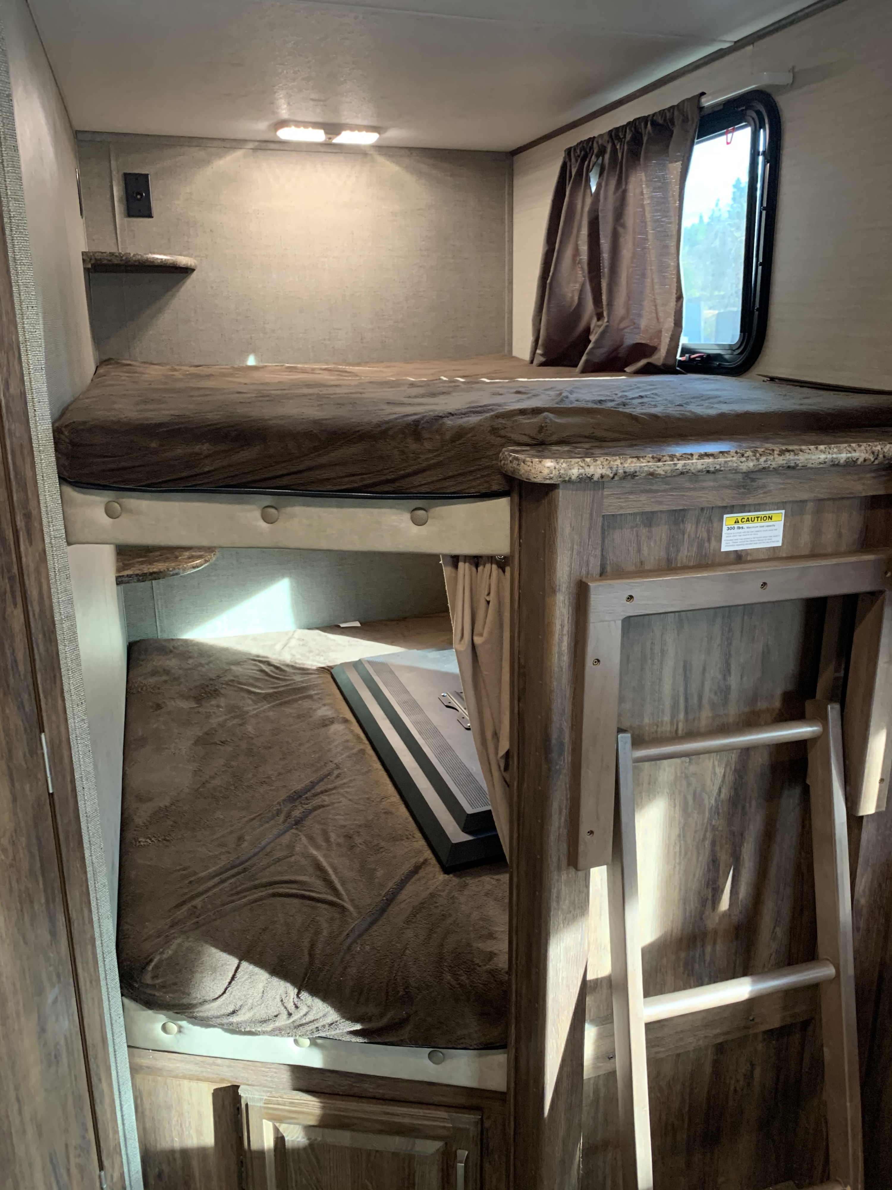 An RV rental interior featuring comfortable bunk beds, a window with curtains, and a ladder for easy access.. Keystone Cougar Half-Ton 2017
