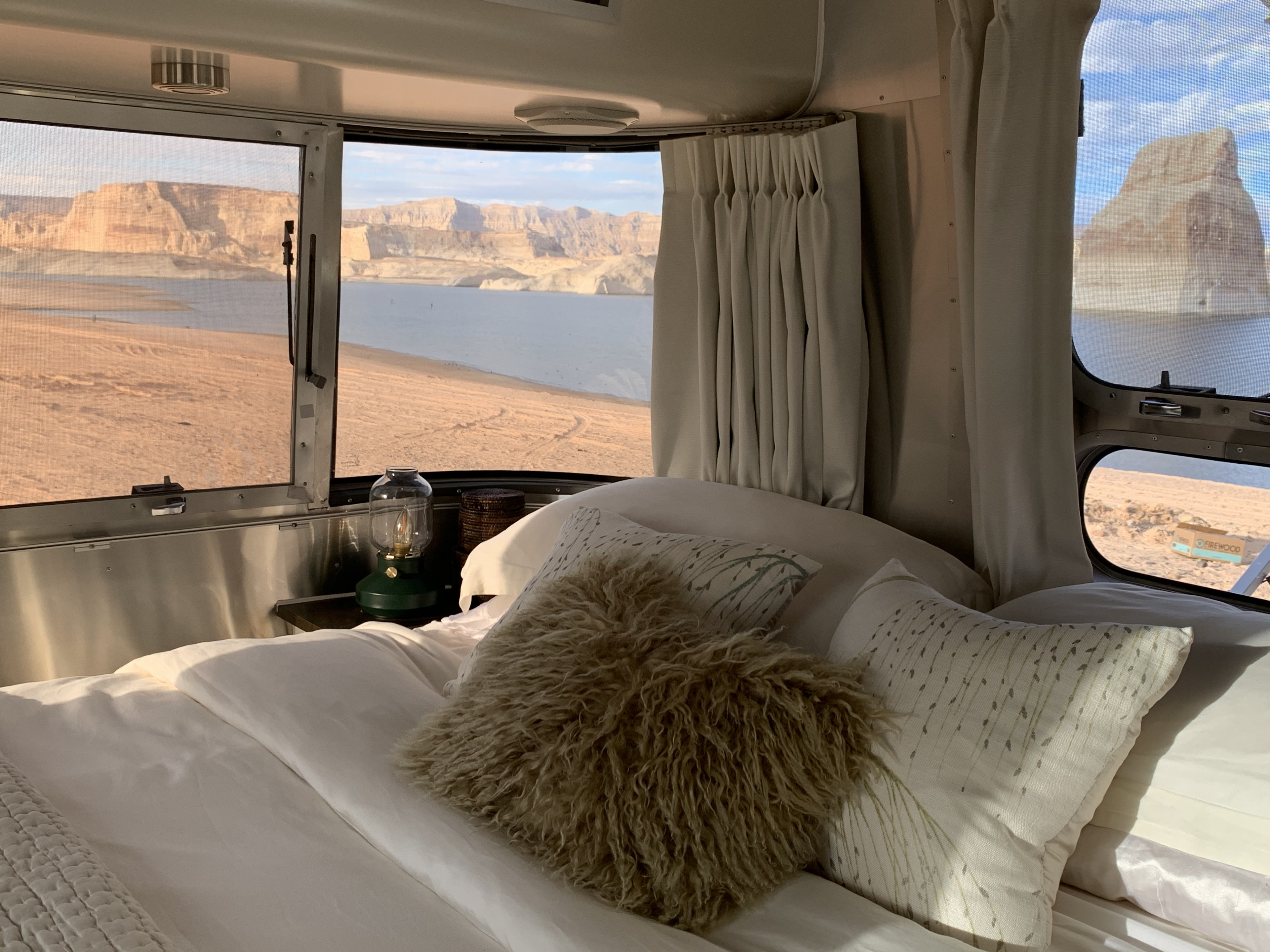 Enjoy glamping with an RV rental! Cozy bed inside a camper offers epic panoramic desert lake views outside the windows.. Airstream Other 2011
