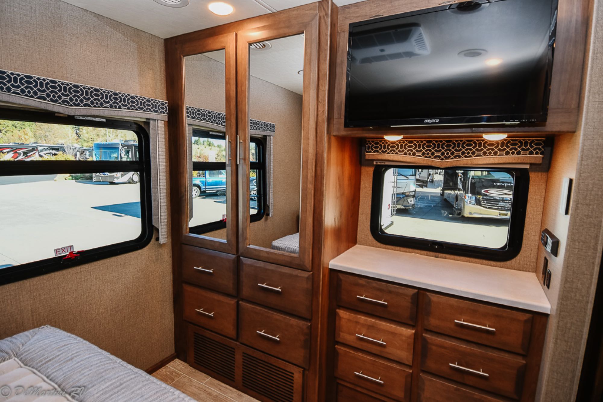 Cozy RV rental interior with bed, mirrored wardrobe, wall-mounted TV, and storage, perfect for your next adventure.. Thor Motor Coach Other 2021