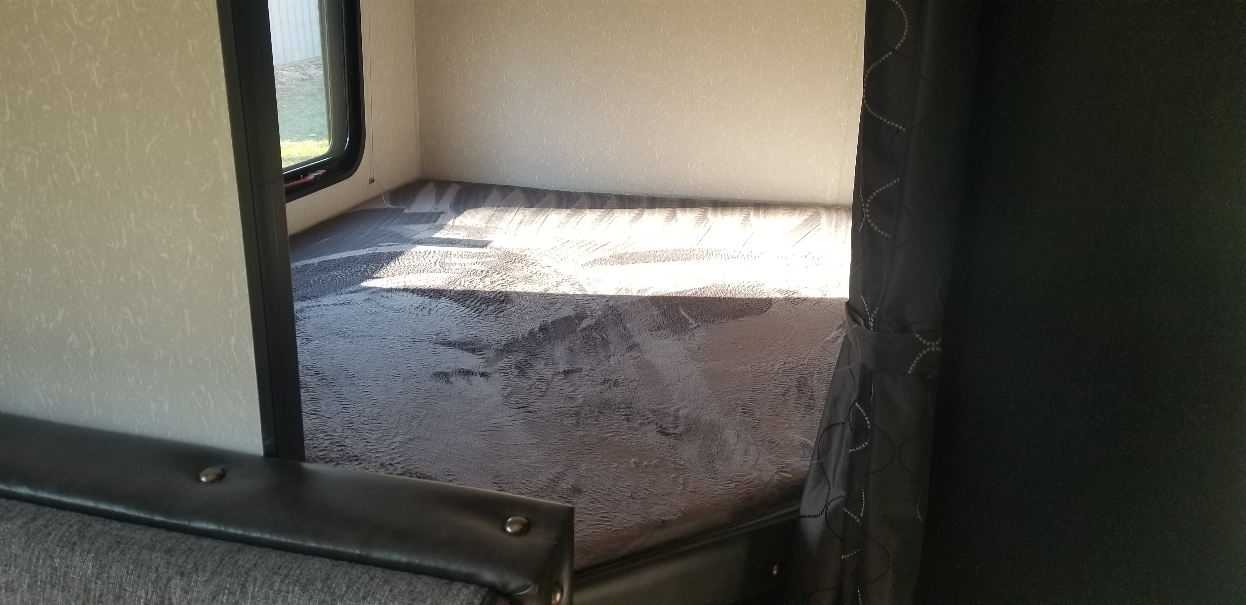 Inside an RV rental: a sunlit, compact bunk bed with mattress and window, ready for adventure.. Forest River Cherokee Grey Wolf 2021