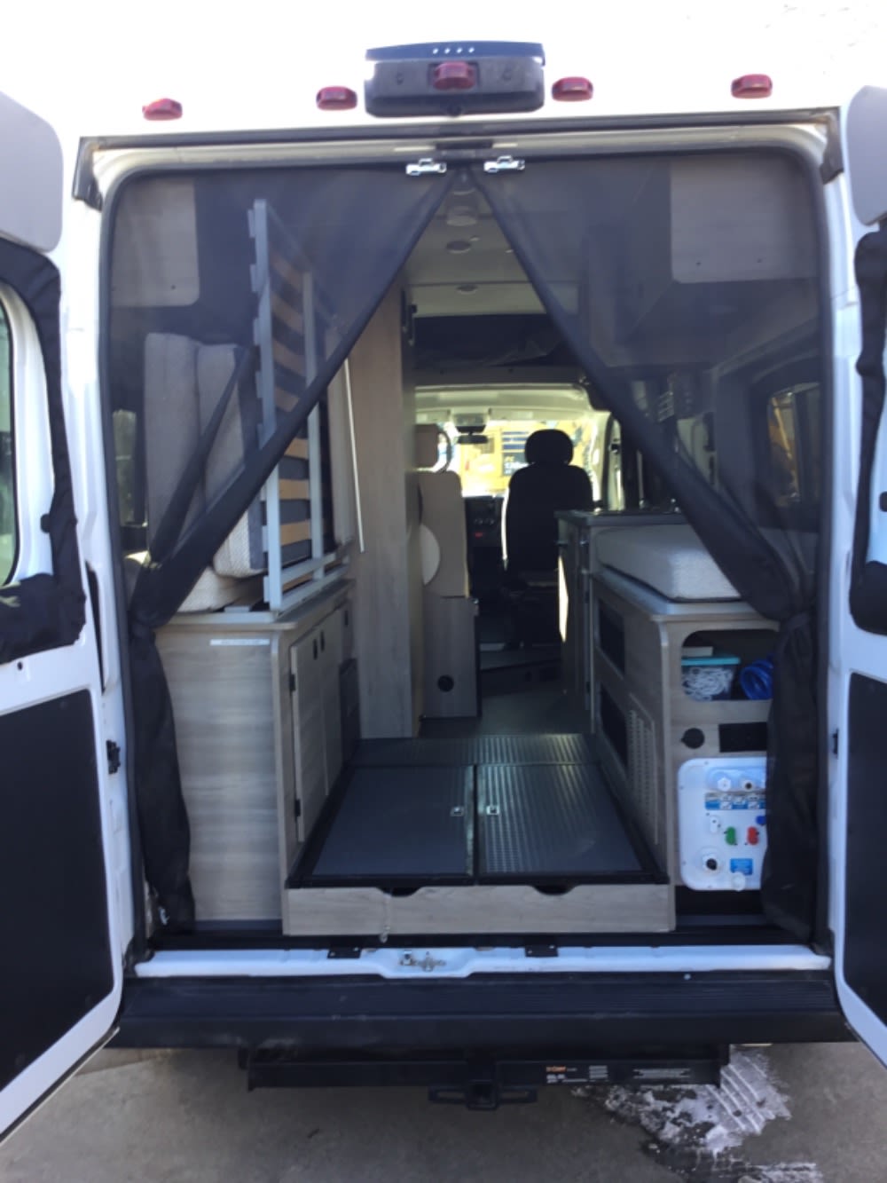 This RV rental shows a camper van interior with a rear screen, modular bed, and custom storage cabinets.. Winnebago Solis 2021