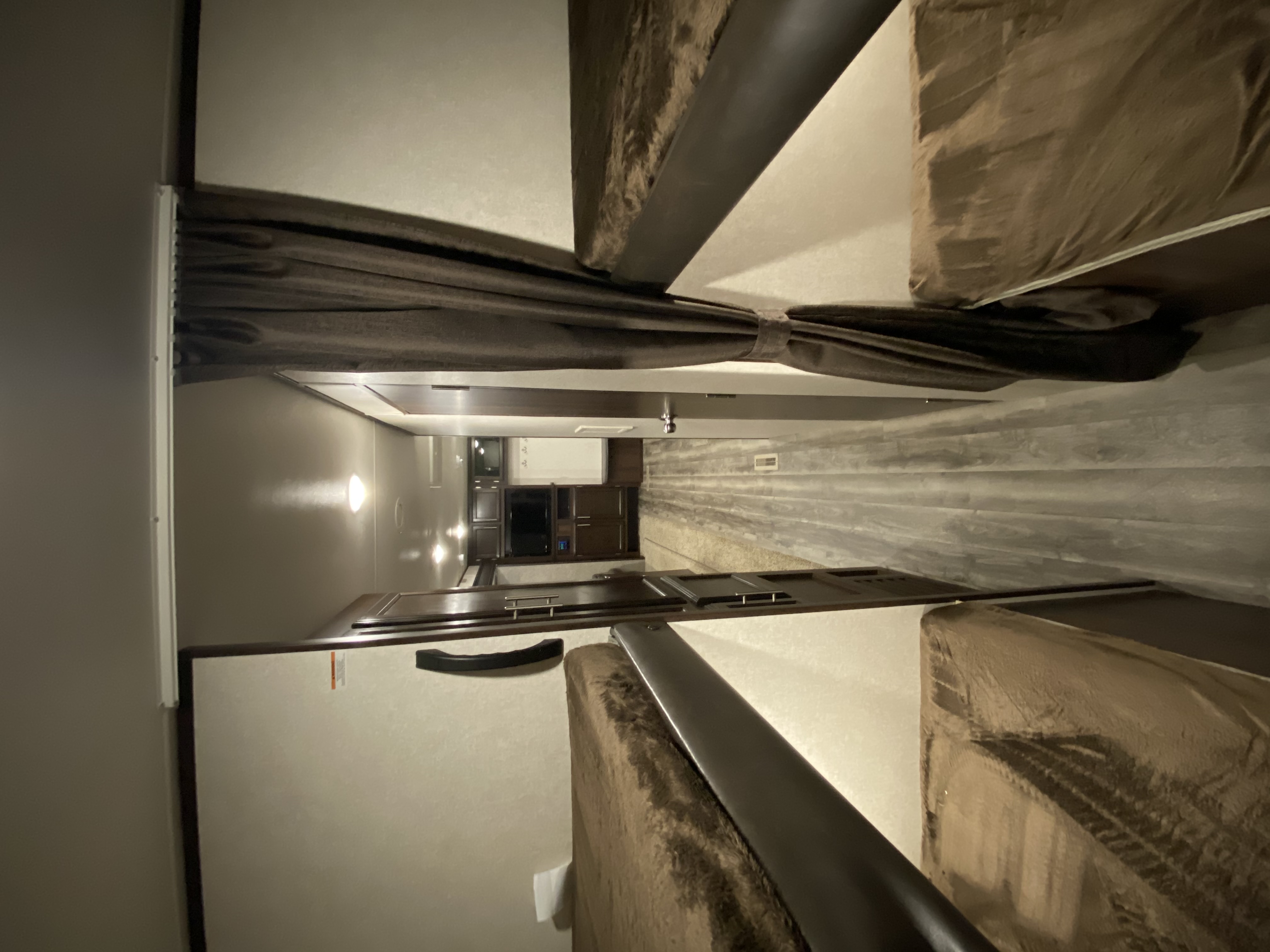 Step into this cozy rv rental. View of bunk beds with dark rails and a tied-back curtain, leading to a kitchen area.. Jayco Jay Flight SLX8 294QBS 2020