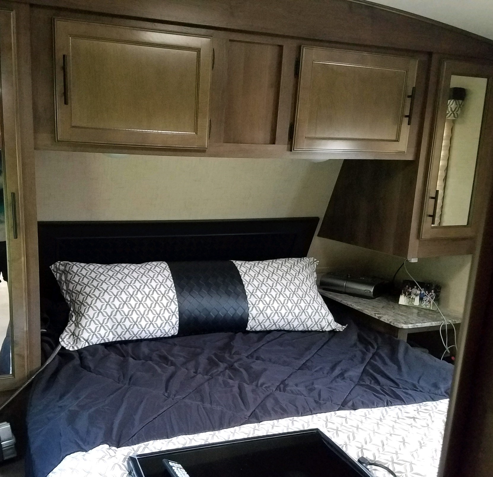 Interior view of an RV rental bedroom, featuring a neatly made bed with decorative pillows and convenient overhead storage.. K-Z Spree S-261RKS 2018