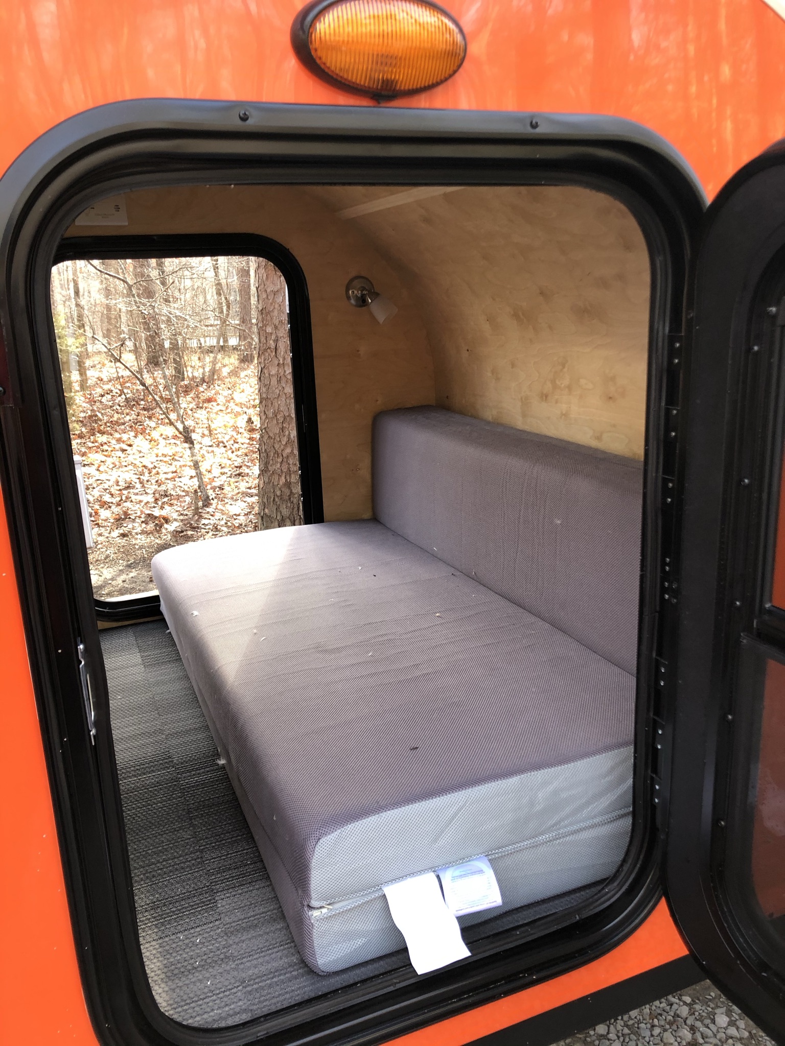 Step inside this cozy RV rental camper, featuring a comfortable bed, warm wood interior, and a serene window view of nature.. Other Other 2021