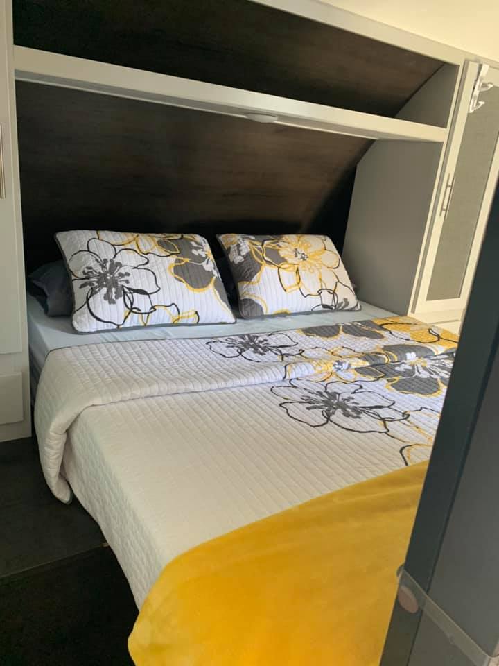 Relax in this RV rental bedroom featuring modern white & yellow floral bedding and built-in storage.. Keystone RV Bullet Ultra Lite 2021