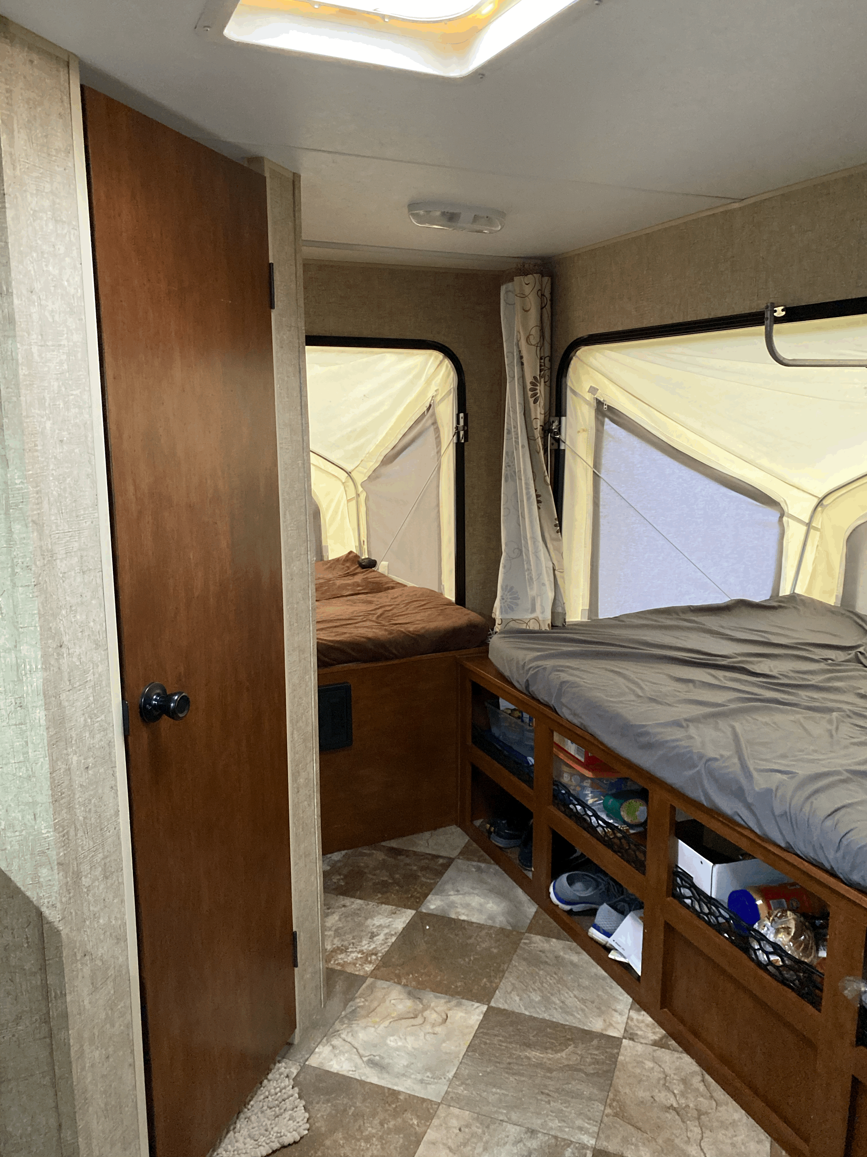 Inside an RV rental: two beds in pop-out sections, under-bed storage, and a door, offering compact camper comfort.. K-Z Manufacturing Sportsman Classic 2015
