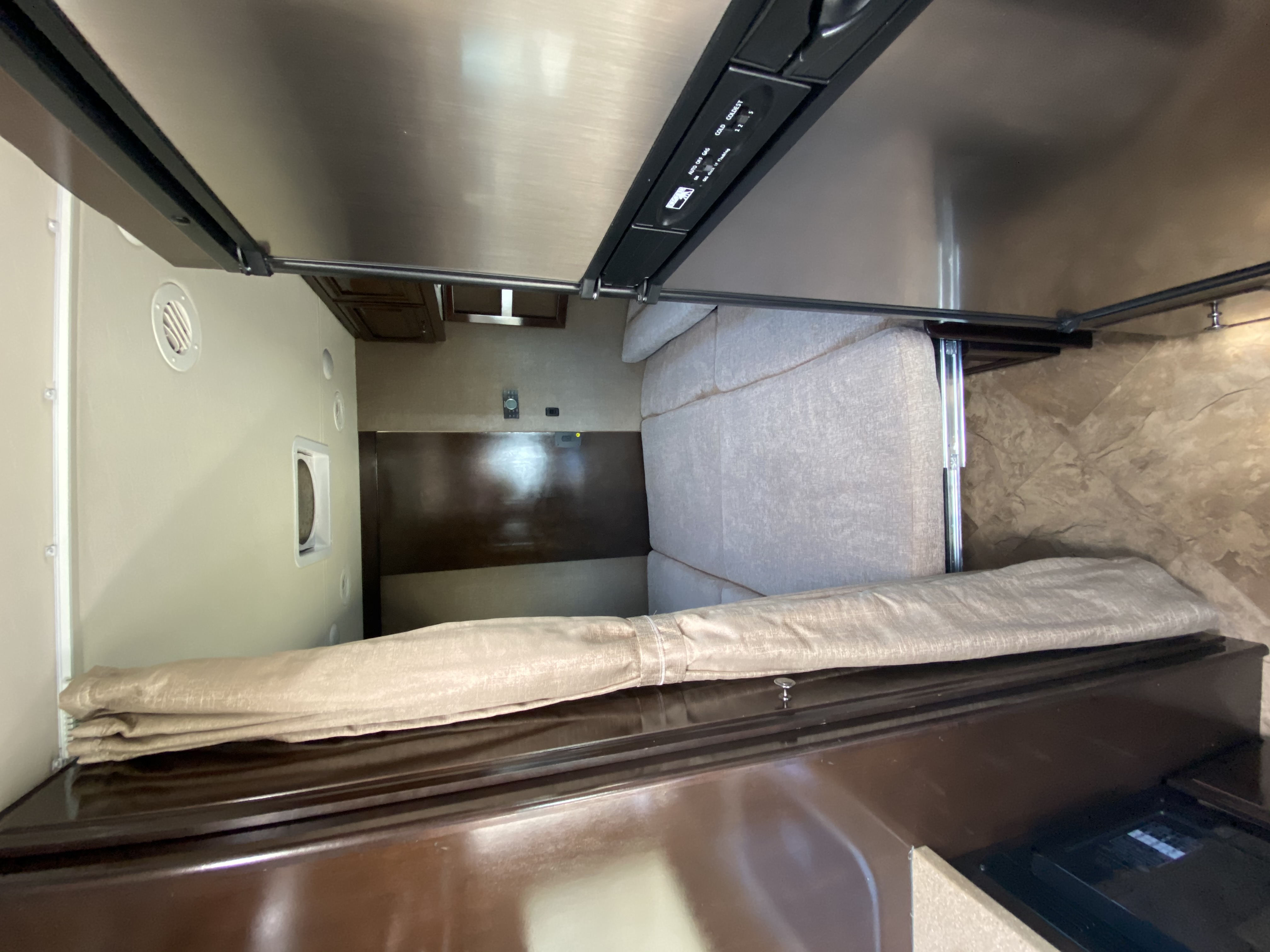 RV rental interior: cozy convertible sofa/bed with overhead bunk and compact fridge controls, perfect for travel.. Thor Motor Coach Citation 2018