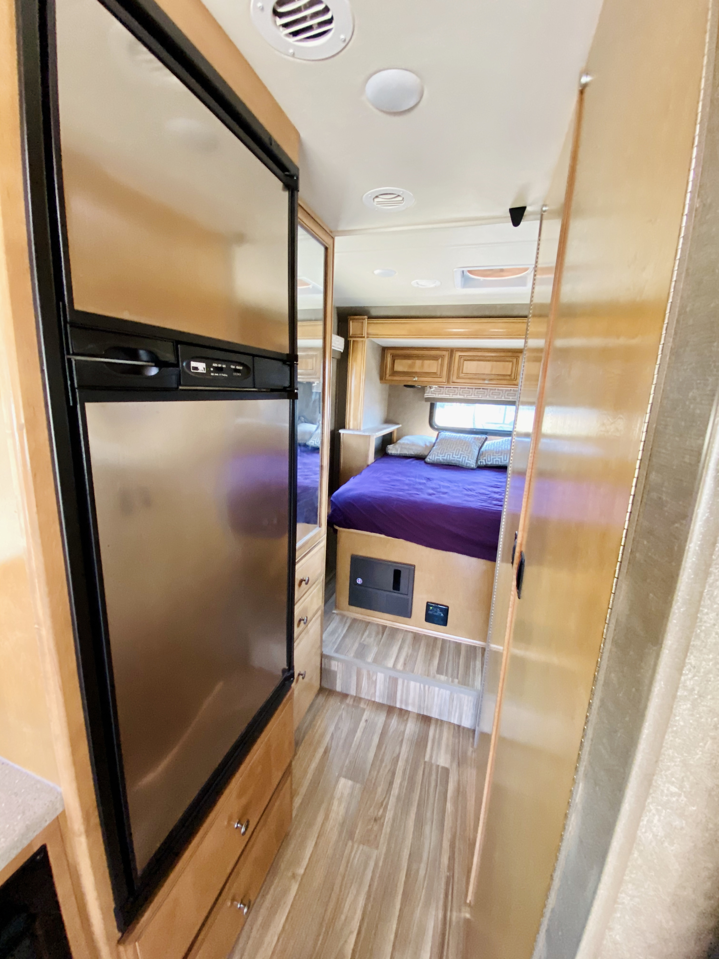 RV rental interior: stainless steel fridge, wood accents, and cozy bedroom with purple bedding.. Thor Motor Coach Other 2016