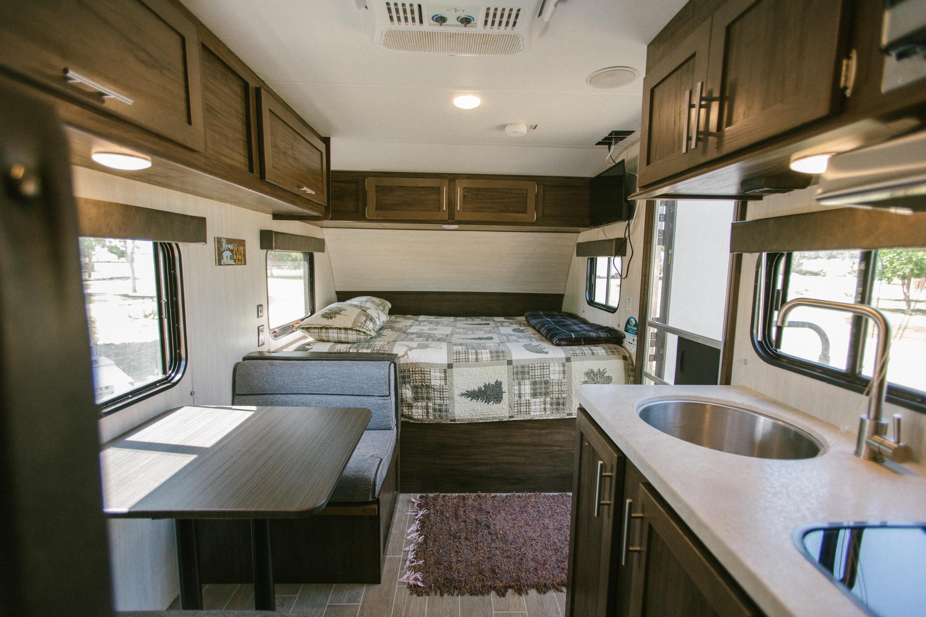 This inviting RV rental interior shows a comfortable bed, dinette, and well-equipped kitchen. Perfect for adventures.. Forest River Cherokee Wolf Pup 2020