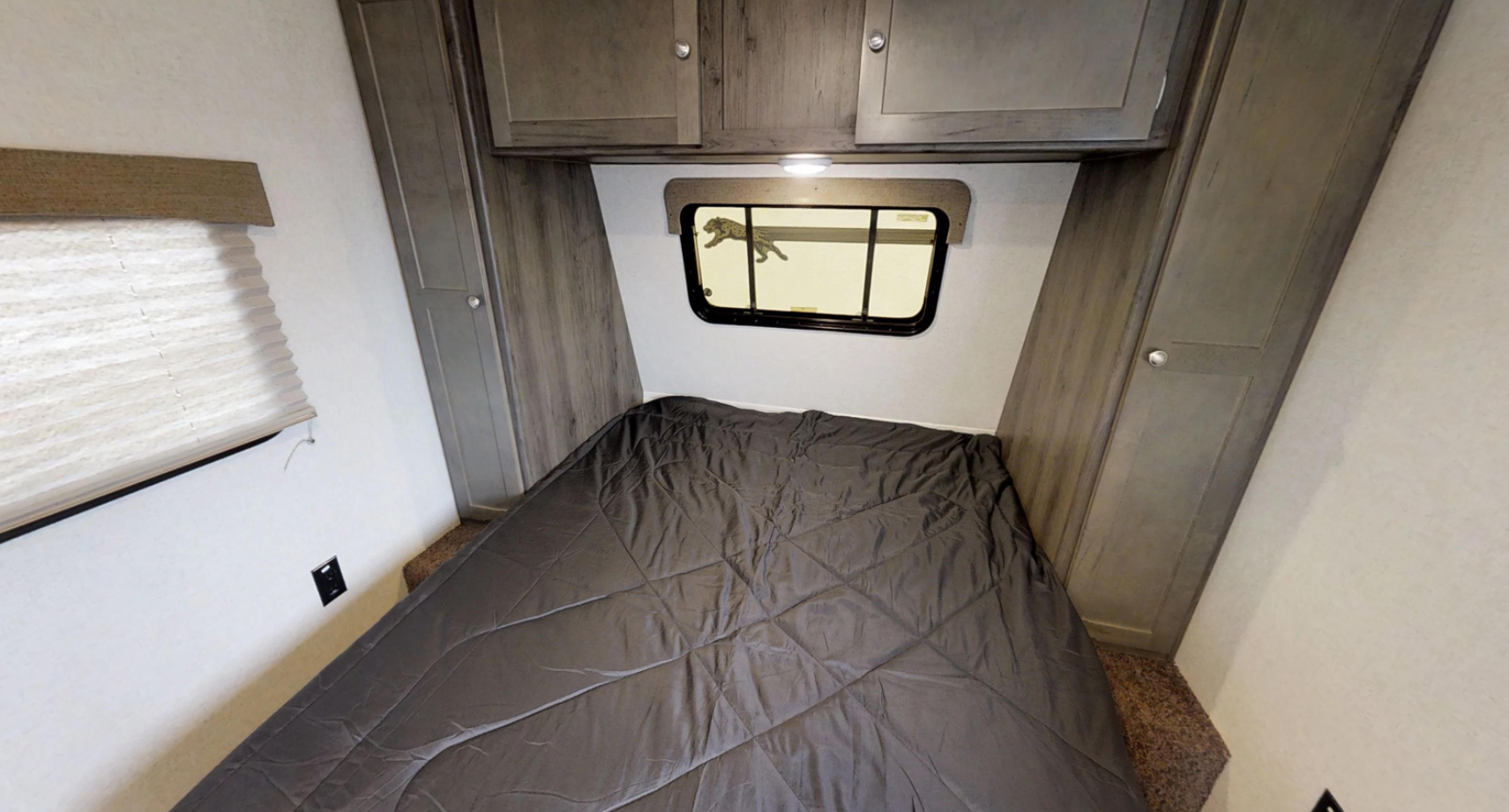 RV rental bedroom with a bed, overhead cabinets, and a window featuring a unique leopard reflection. Perfect for your travels.. Clipper Clipper Trailer 2019