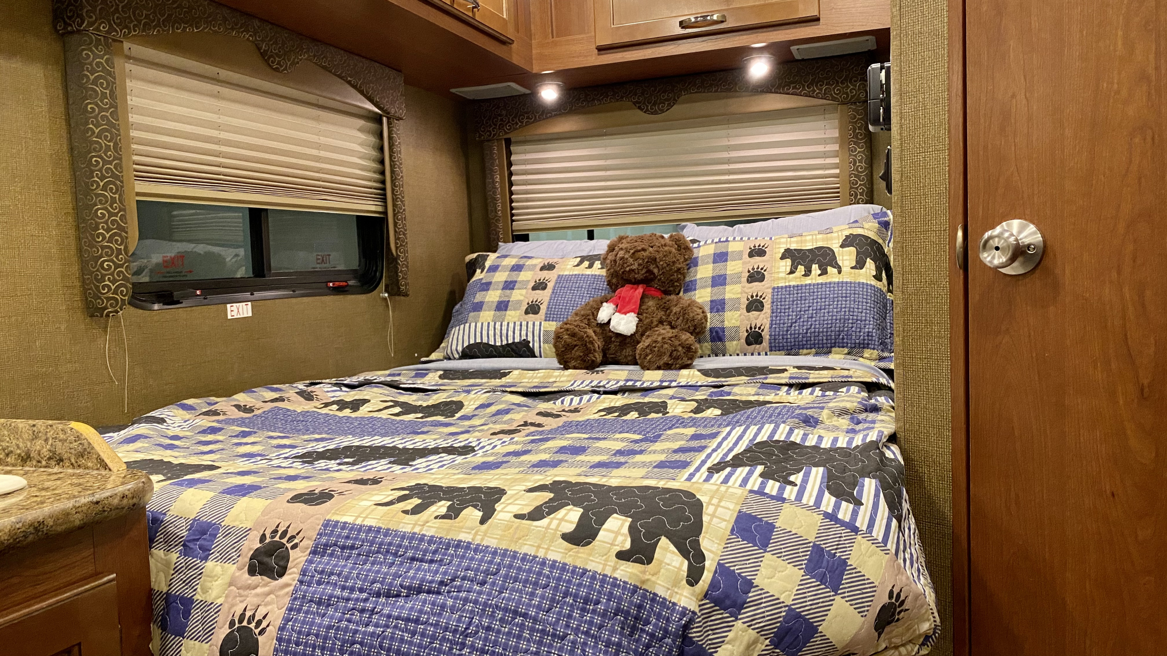 Enjoy a cozy RV rental bedroom: bear-themed quilt, teddy bear, and warm lights await your adventure.. Thor Motor Coach Freedom Elite 2016