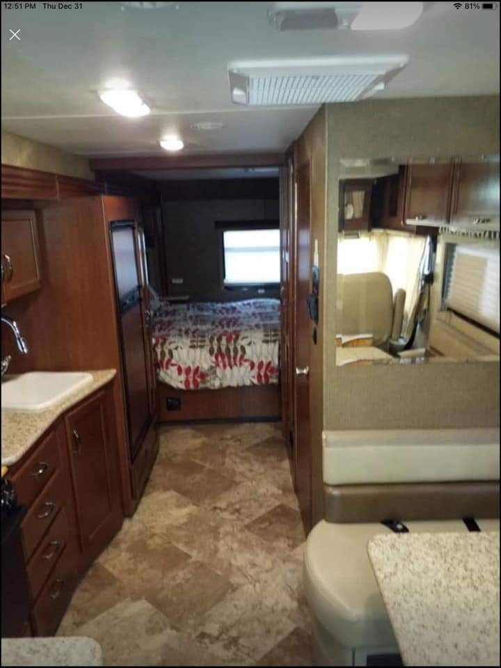 View inside a clean RV rental: kitchen with sink, fridge, dinette, and rear bedroom with window visible.. Thor Motor Coach A.C.E 2015