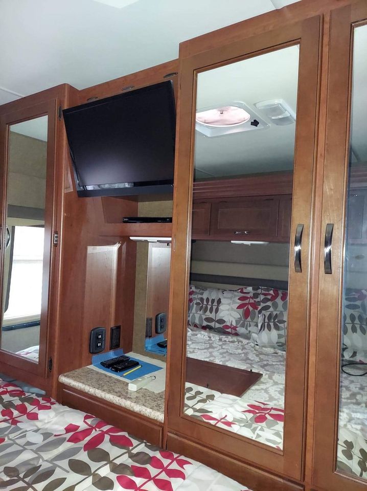 This RV rental bedroom features a TV, ample mirrored storage, and a comfy bed with floral sheets for your travels.. Thor Motor Coach A.C.E 2015