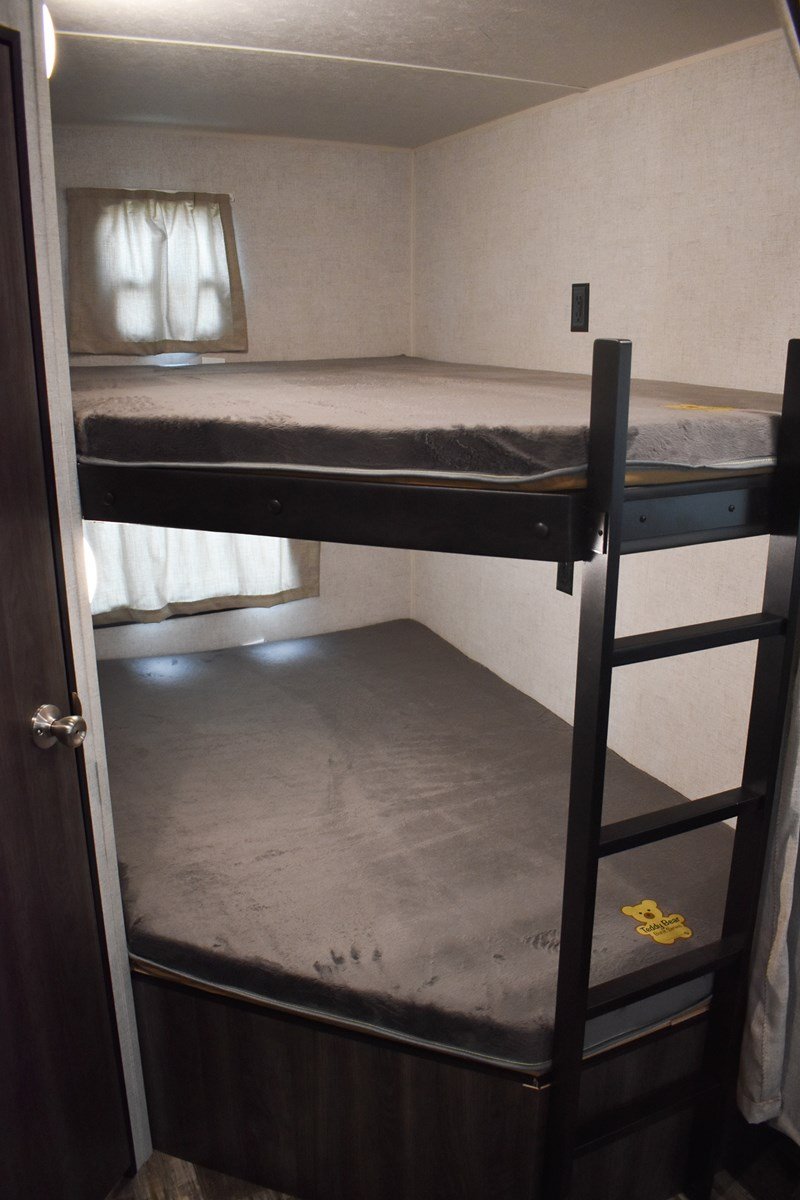 RV rental bunkhouse: two cozy beds with grey mattresses, windows, and ladder. Perfect for family sleeping arrangements.. Starcraft Autumn Ridge 2020