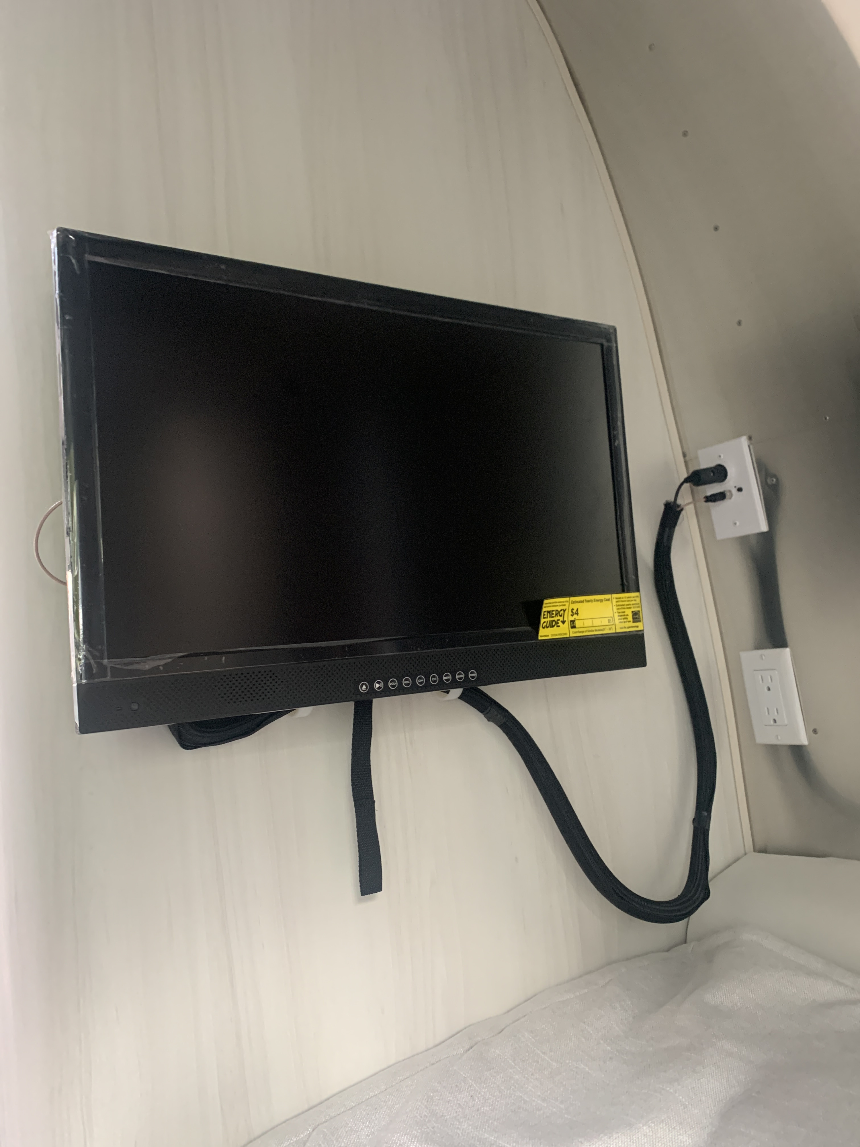 Wall-mounted TV and power outlets inside an RV rental, providing entertainment and convenience in a compact space.. Airstream Bambi 16” 2021