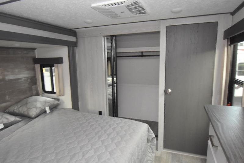 Explore this RV rental's modern bedroom: plush gray bed, compact closet, and cool AC, perfect for travel.. Other Other 2022