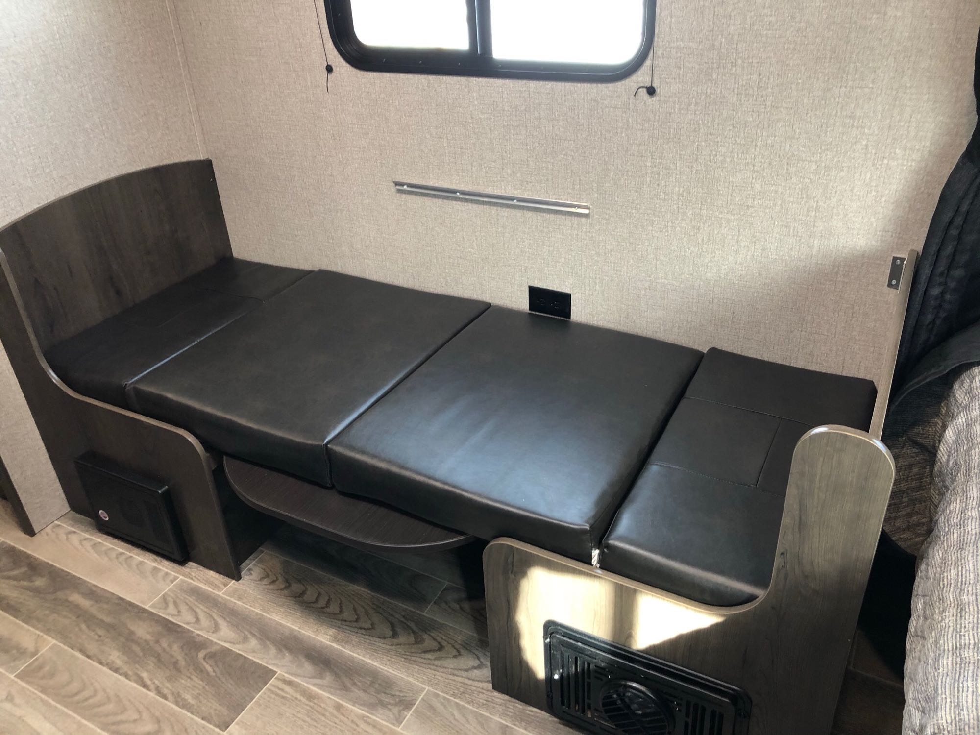 RV rental interior: Versatile black cushion seating/bed area with wood-look base, wall outlet, and window.. Jayco Jay Flight SLX Baja Edition 2021