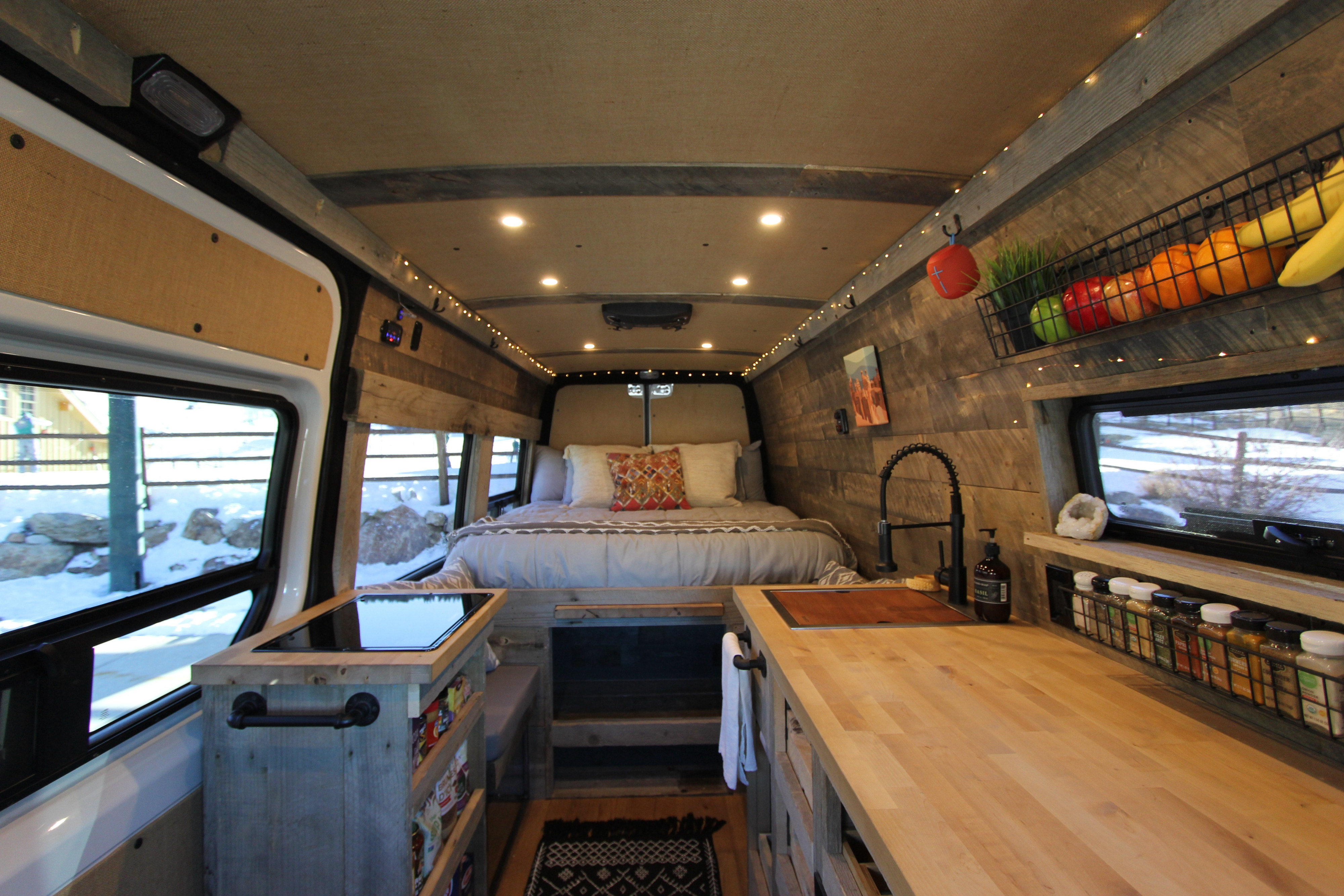 Cozy custom RV rental interior with a spacious bed, fully equipped kitchen, and warm lighting, perfect for van life adventures.. Mercedes-Benz Sprinter 419 LWB High Roof 2020