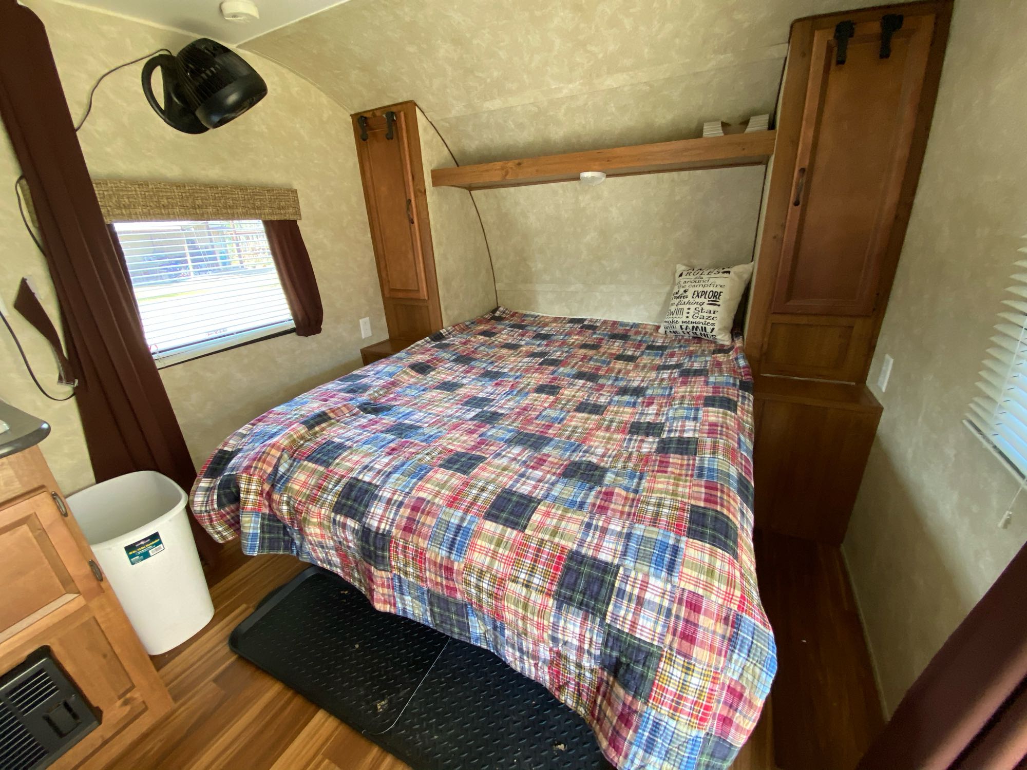 Inside an RV rental: a comfy bedroom with a colorful patchwork quilt, window, and ceiling fan. Ideal for travel.. Gulf Stream Kingsport 2015