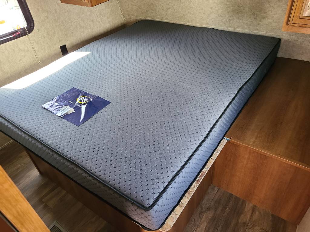 A new, light grey Sealy mattress with black trim on a wooden bed frame inside an RV rental. Ready for your travels.. Prime Time Avenger 2018