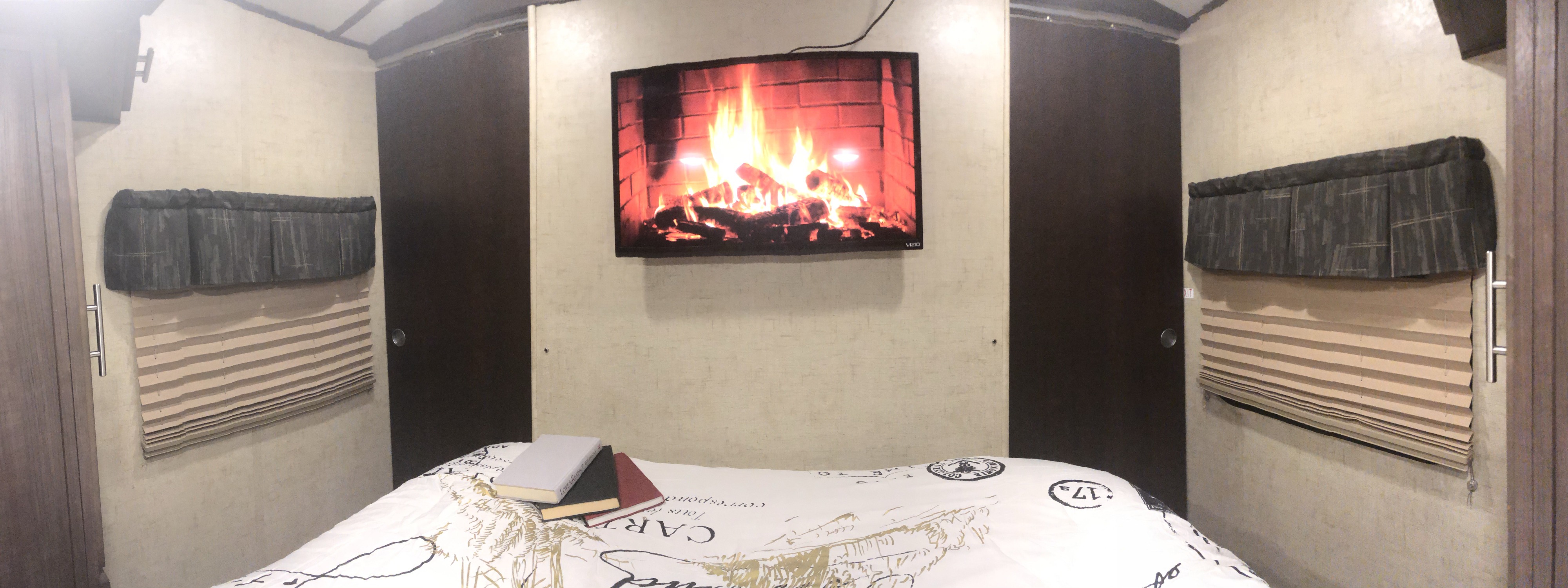 Cozy RV rental bedroom features a fireplace TV, bed, privacy doors, and windows.. Forest River Surveyor 2016