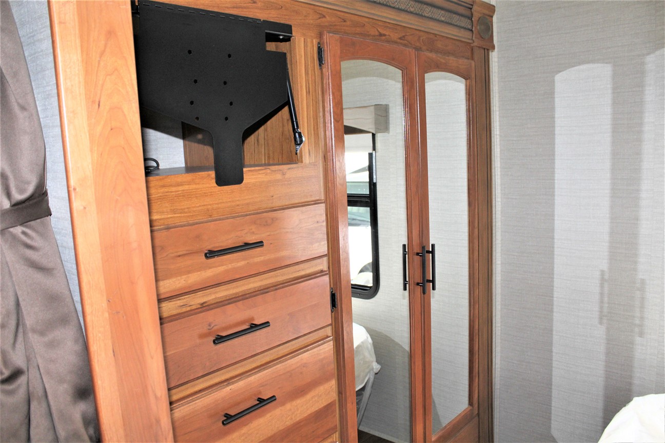 RV rental bedroom: wooden dresser, TV mount, mirrored closet, and window.. Jayco Greyhawk 2017