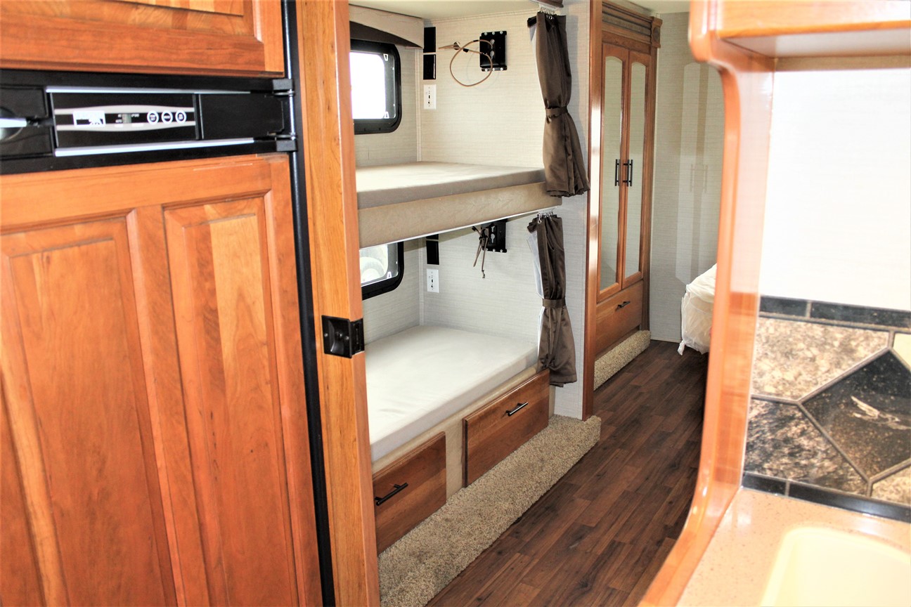 RV rental interior: bunk beds, refrigerator, wardrobe, and partial kitchen view, providing ample space for travelers.. Jayco Greyhawk 2017