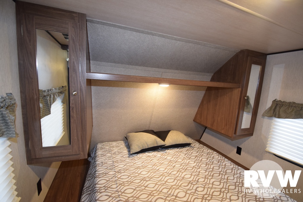 Inside an RV rental: a cozy bedroom with a bed, overhead shelf with lighting, and mirrored storage cabinets.. Heartland Prowler Lynx 2018
