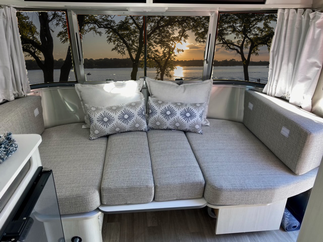 Enjoy this RV rental's cozy Airstream living space. Sunset over the lake, seen from comfy seating.. Airstream Bambi 16RB 2020