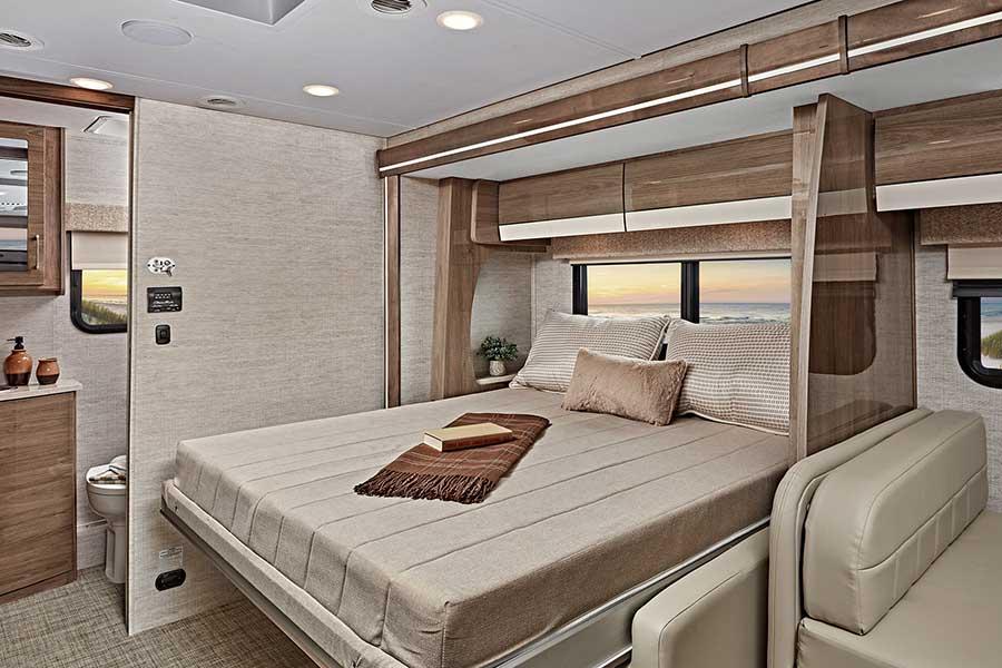 This cozy RV rental bedroom features a large bed, beach window view, and smart, space-saving design for travelers.. Entegra Coach Qwest 2021