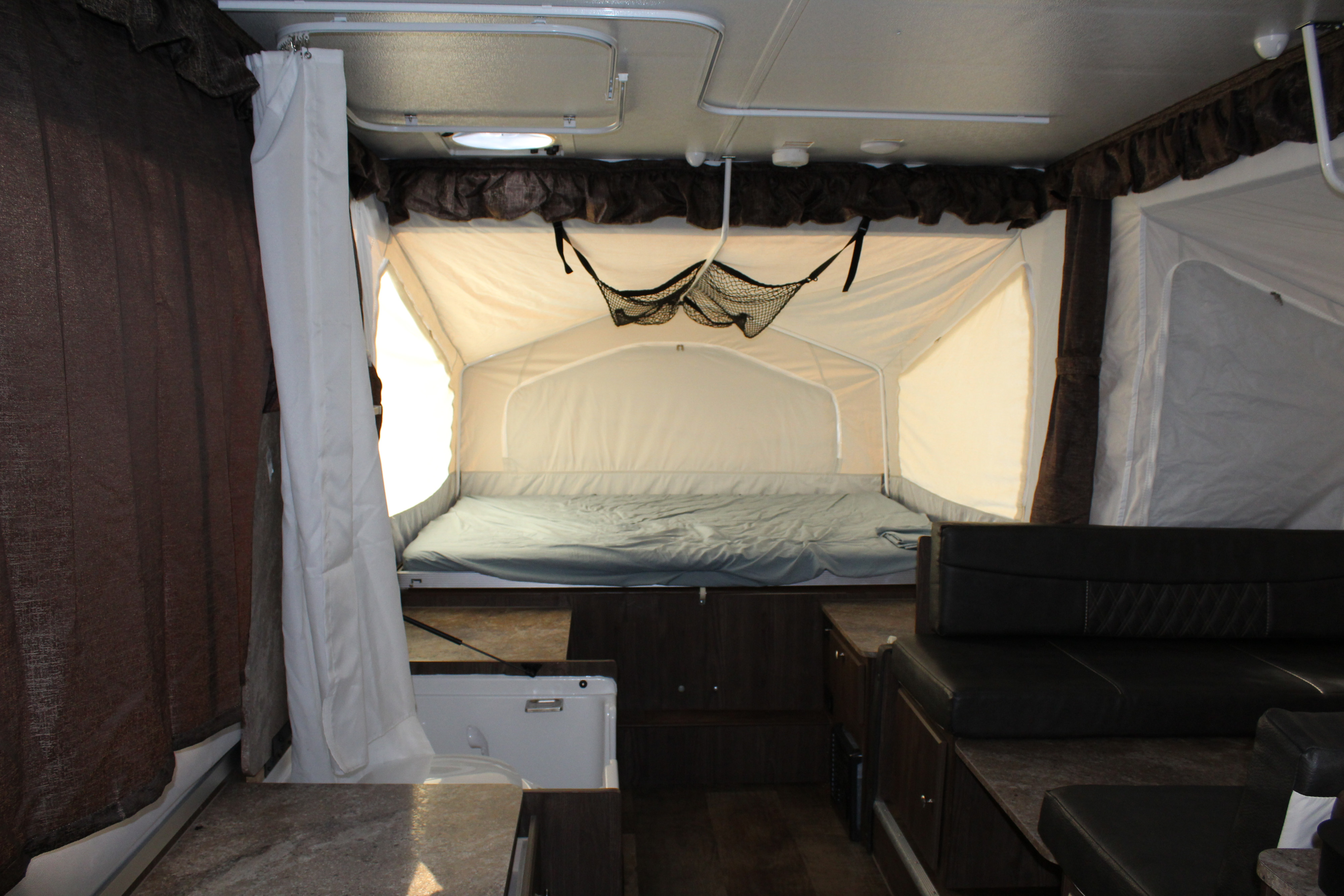Inside an RV rental pop-up camper: comfy bed, dinette, and compact bathroom for your travels.. Forest River Rockwood ESP 2017