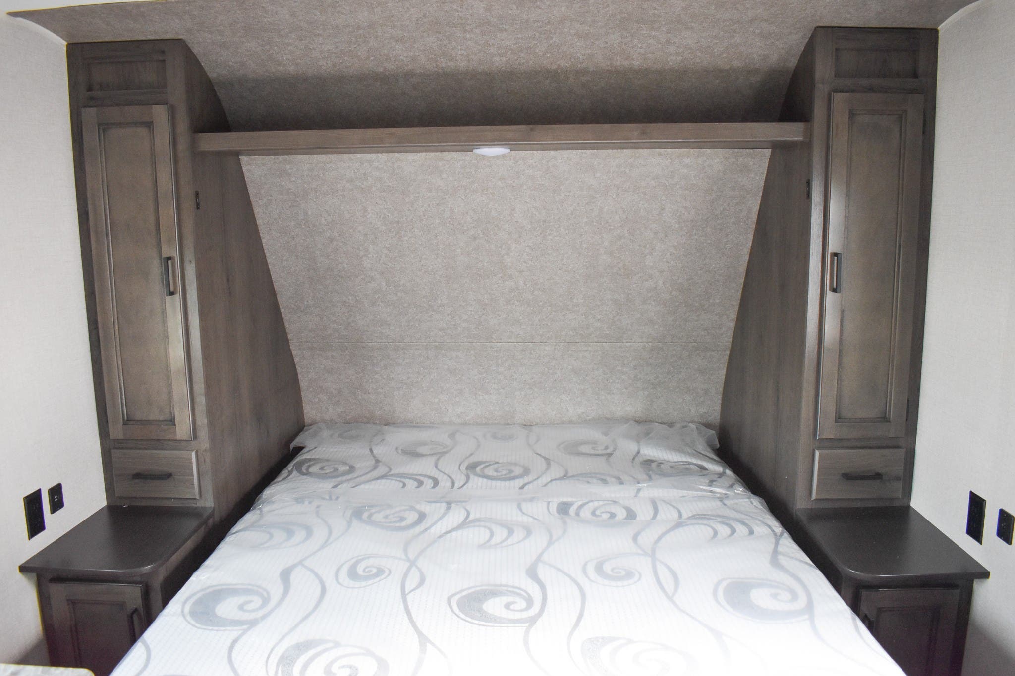 Cozy RV bedroom features a bed, two storage cabinets, and overhead shelving, ideal for your next rv rental trip.. Open Range 20MB 2021