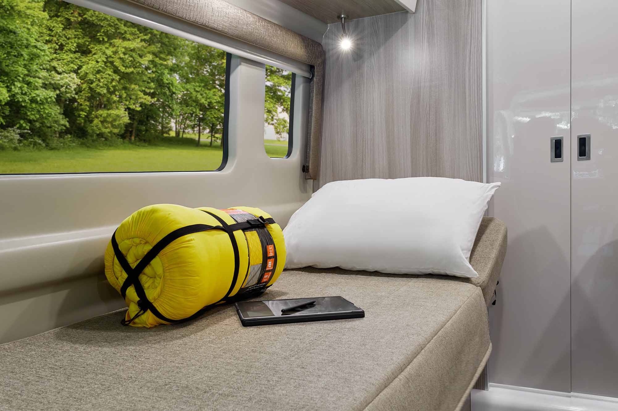 Relaxing RV rental interior: bed, sleeping bag, tablet, & stunning nature view from the window.. Thor Sequence 2021