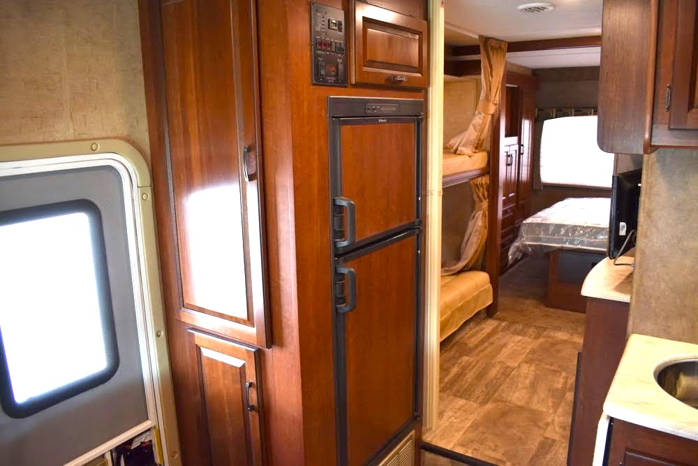 This RV rental interior features a kitchen with fridge, bunk beds, and a main bed area, showing comfortable living space.. Forest River Sunseeker 2015