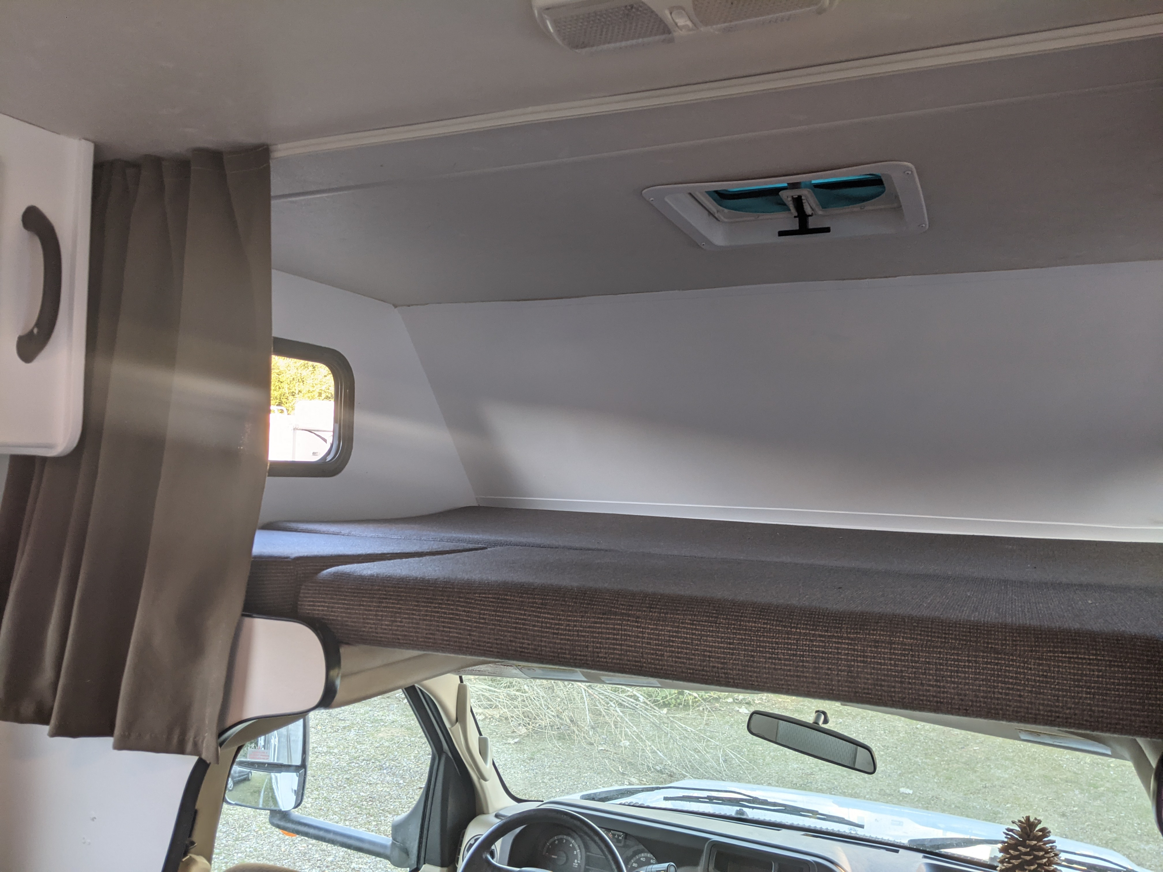 View inside an rv rental, showing the cab-over bunk, front dashboard, and ceiling vent/lights.. Thor Motor Coach Four Winds Majestic 2015