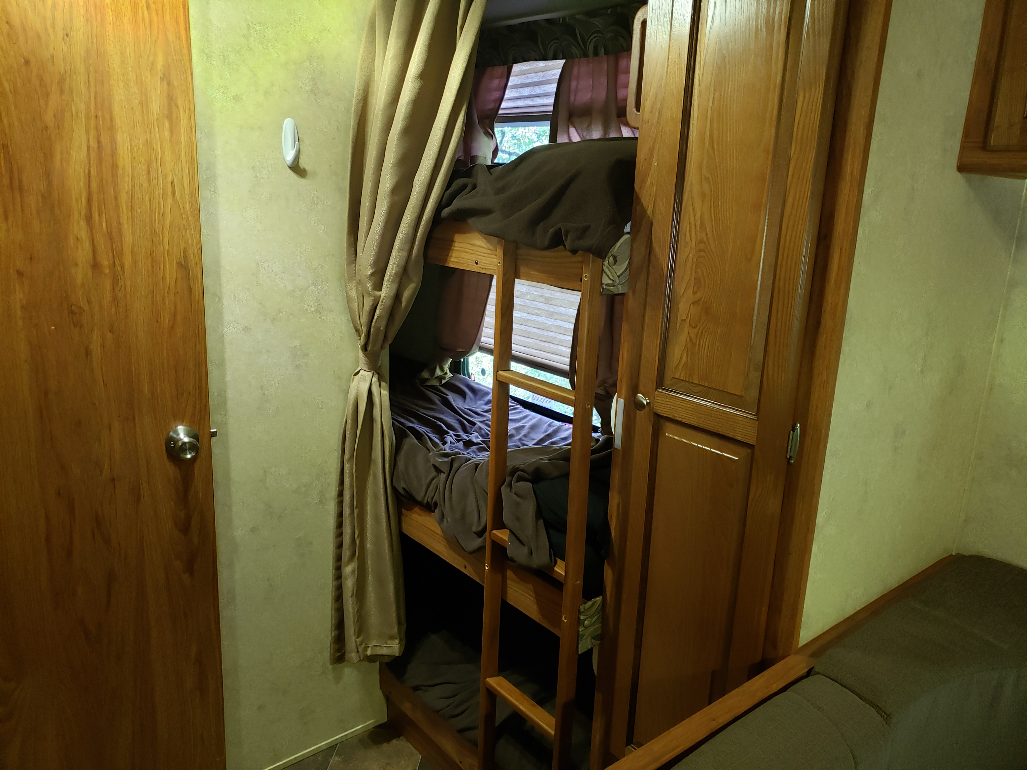 RV rental: Wooden bunk beds with a tied-back privacy curtain, an adjacent wardrobe, and a visible door on the left.. Forest River Inc flagstaff 823D camper trailer 2013