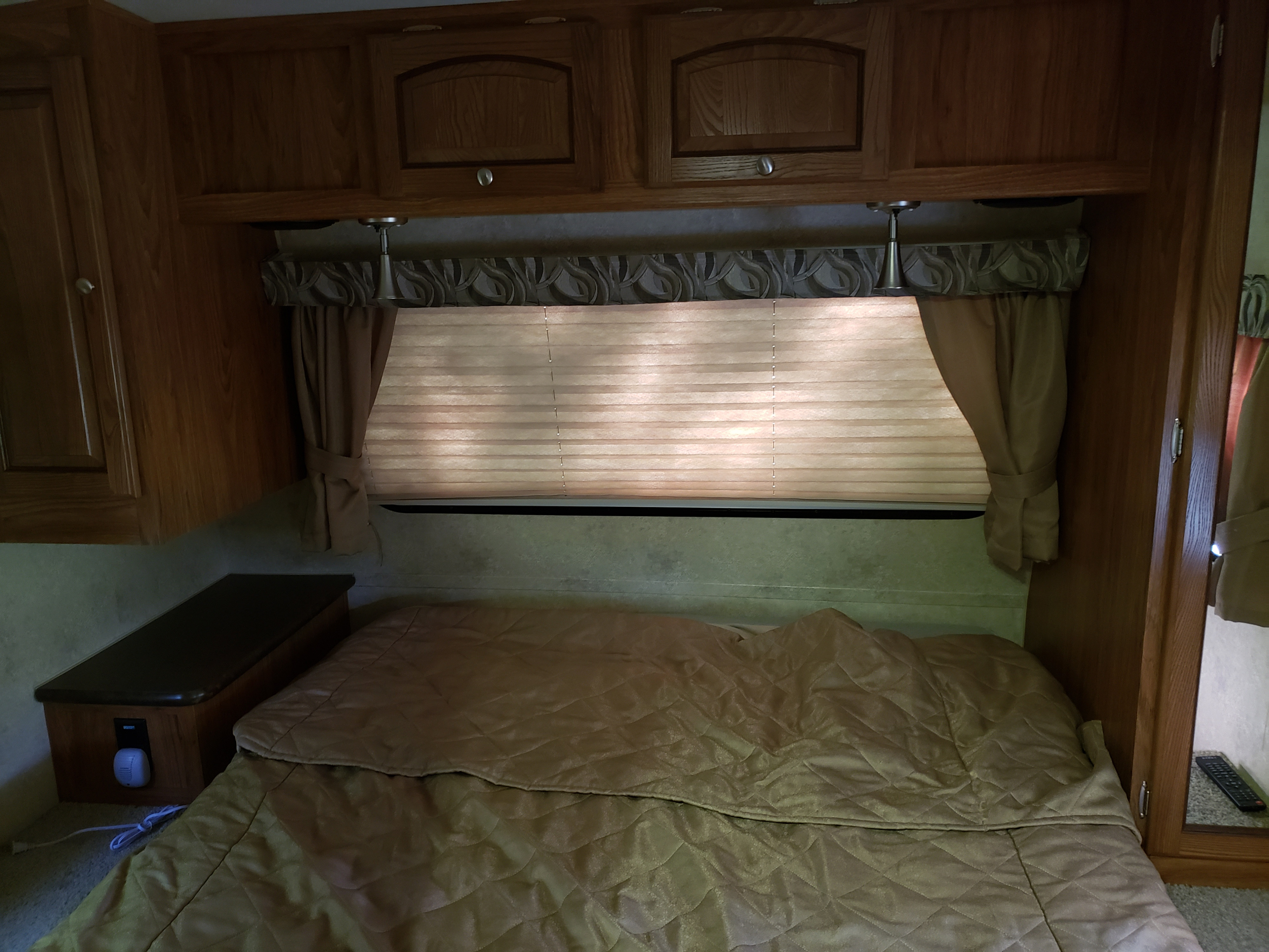 RV rental bedroom interior featuring wood cabinets, window blinds, a comfy bed, and small nightstand.. Forest River Inc flagstaff 823D camper trailer 2013