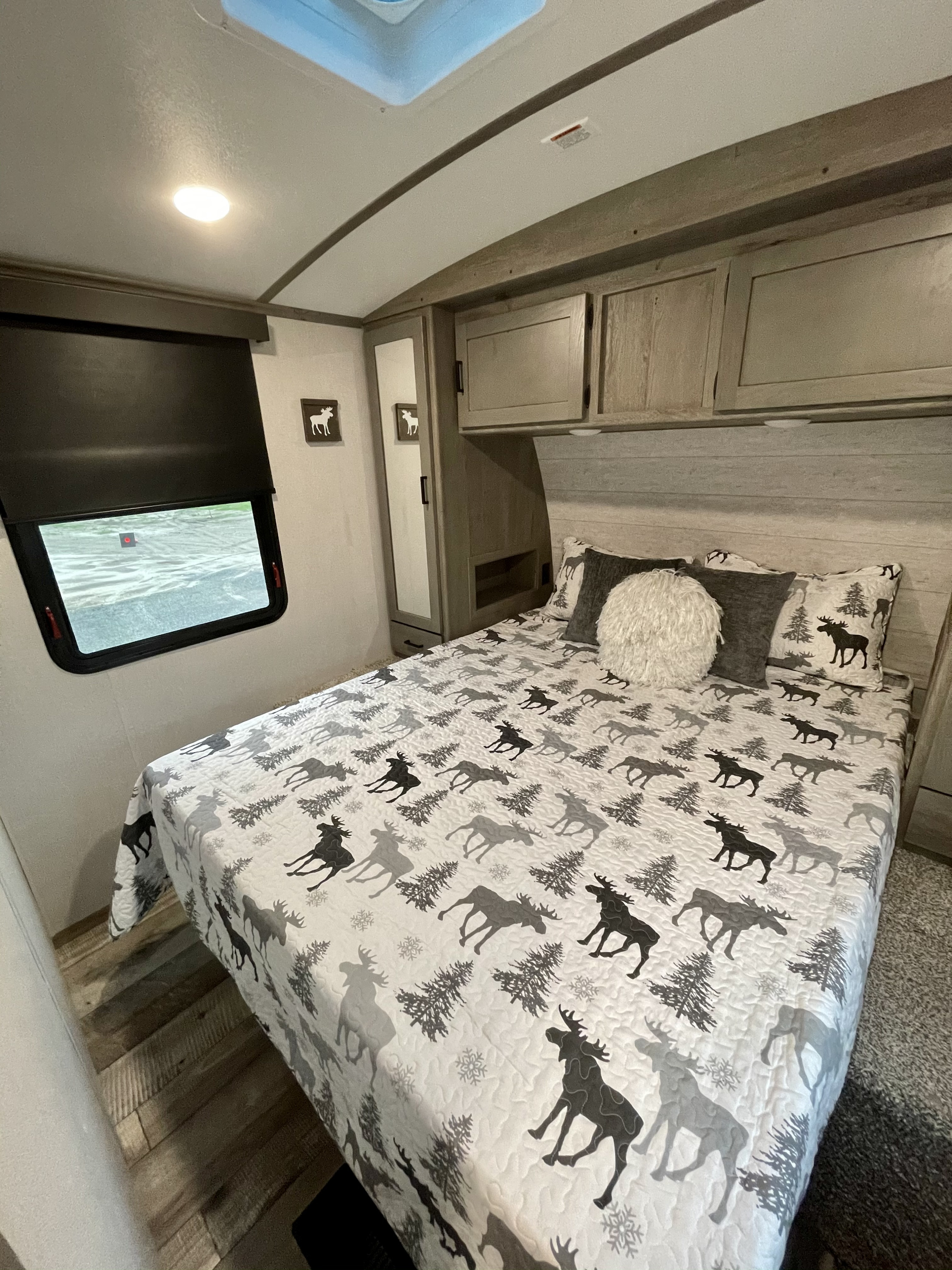 Experience comfort in this RV rental bedroom: moose bedding, wood-look floor, and ample storage for your camping adventure.. Keystone Outback 340BH 2021