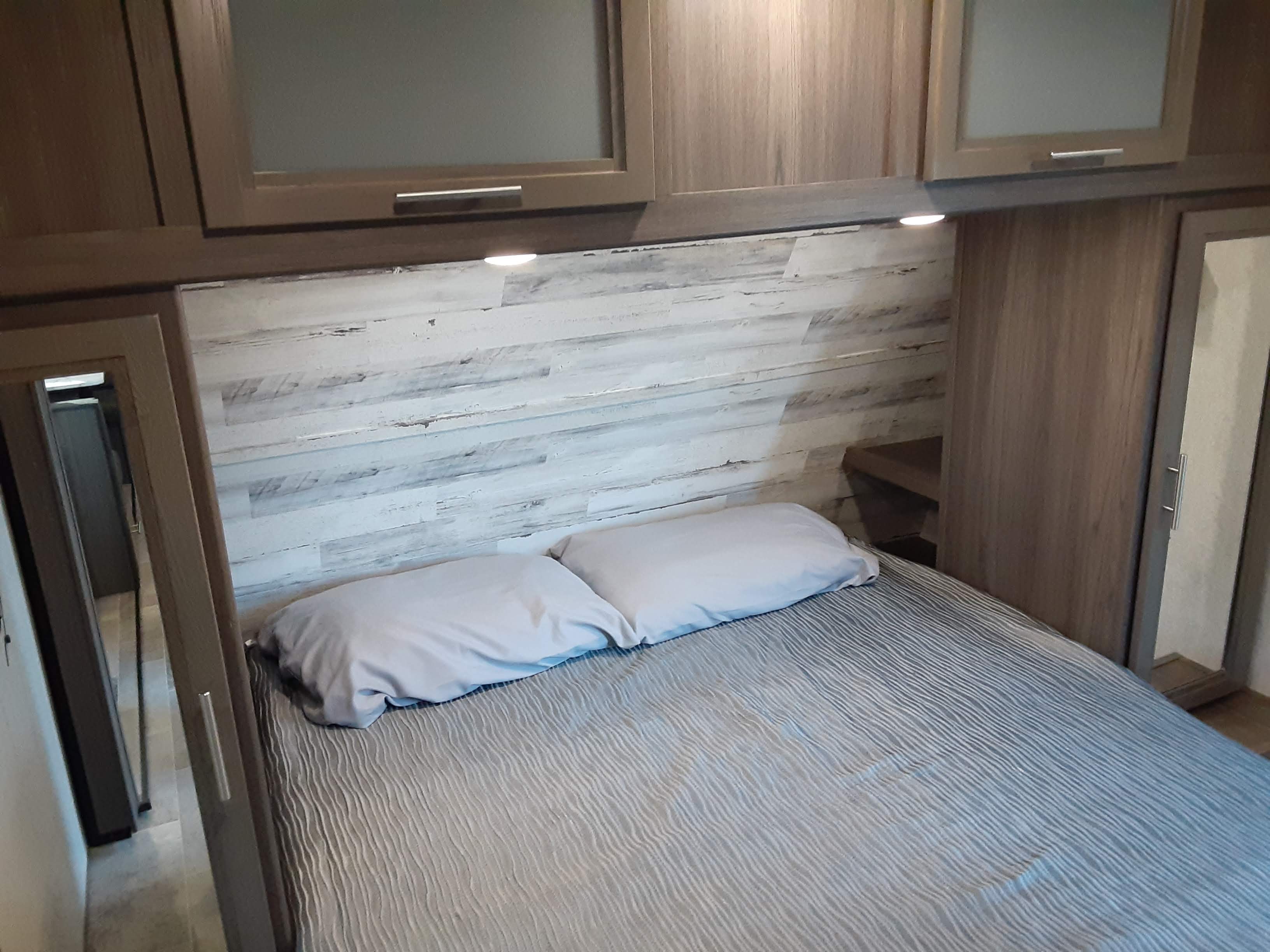 RV rental: Modern bedroom featuring a comfortable bed, overhead cabinets, under-cabinet lighting, and mirrored closet.. Dutchmen Kodiak 2020